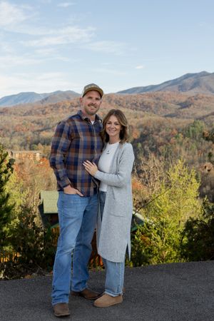 Couple poses together on mountain overlook during fall season.