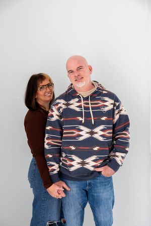 Three photos showing a couple wearing matching navy patterned hoodies and jeans posing playfully against a light background.