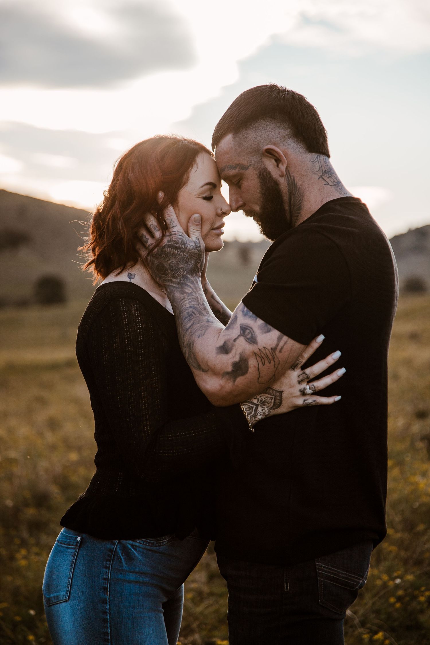 Intimate couple photo session in a field at sunset showing tender moments in silhouette.