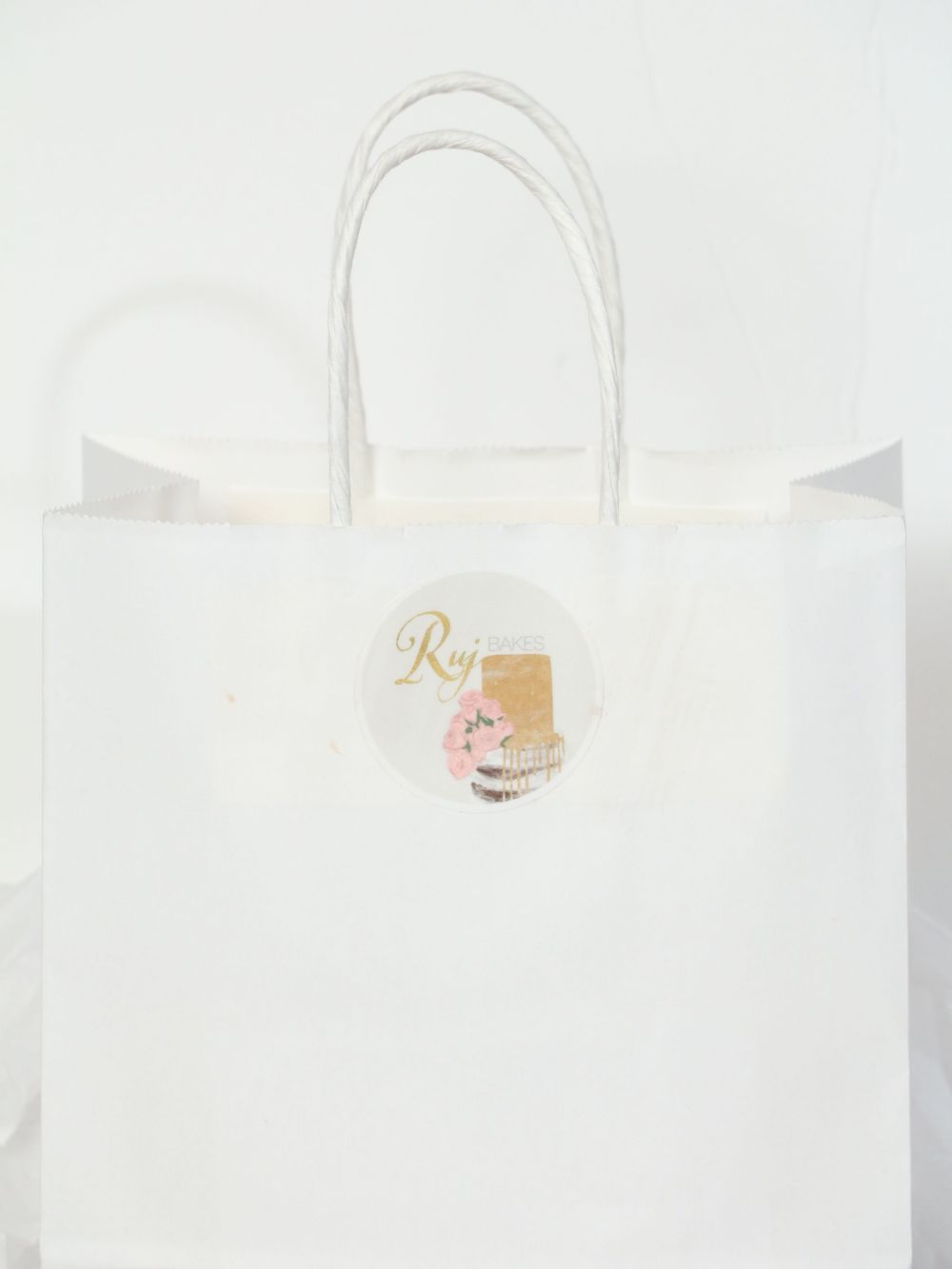 White and gold gift packaging boxes with elegant branding and ribbon details arranged on a clean background.