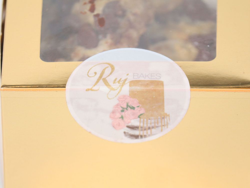 Row of gold bakery boxes with custom branding and clear viewing windows.