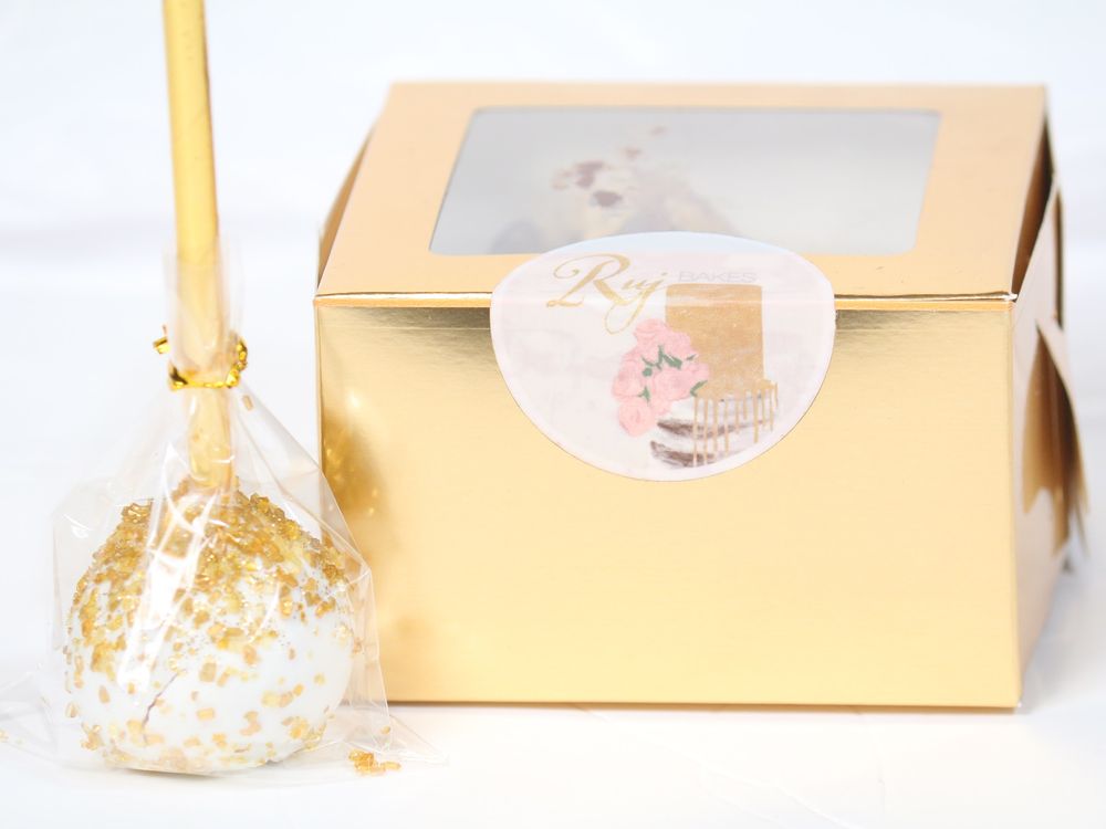 Gold cake boxes with clear windows showing elegant dessert packaging and branding.