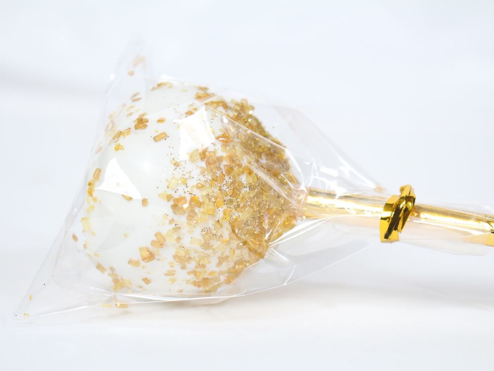 Gold metallic leaf flakes scattered on a white decorative surface for cake embellishment.
