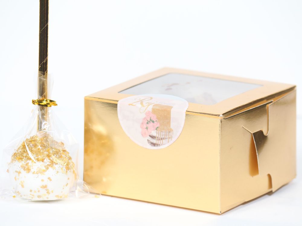 A set of elegant gold designer gift boxes and boxes with gold-tinted glass covers arranged in a clean white display.