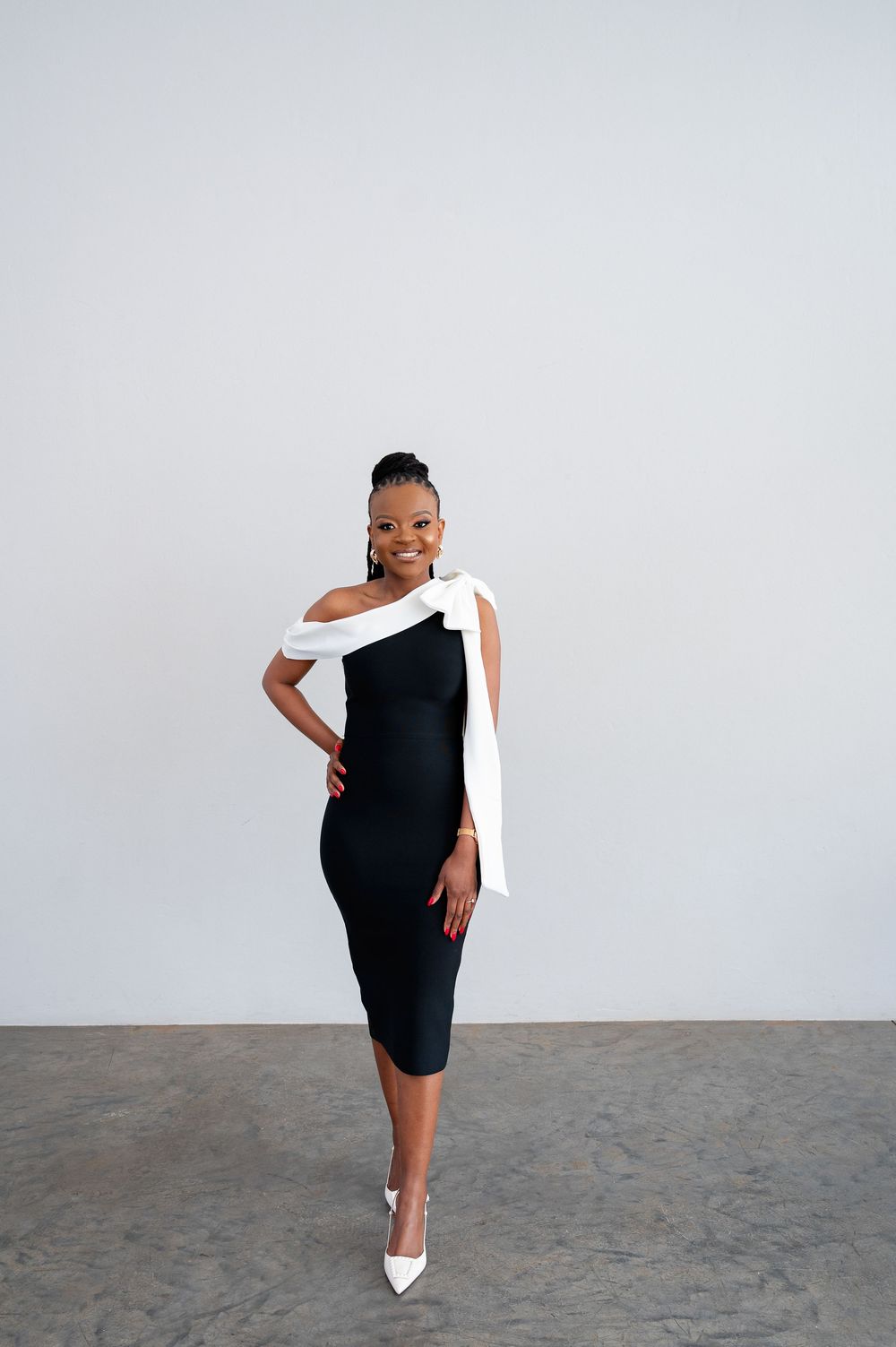 A fashionable black dress and white shoe ensemble shown in elegant poses against a gray background.