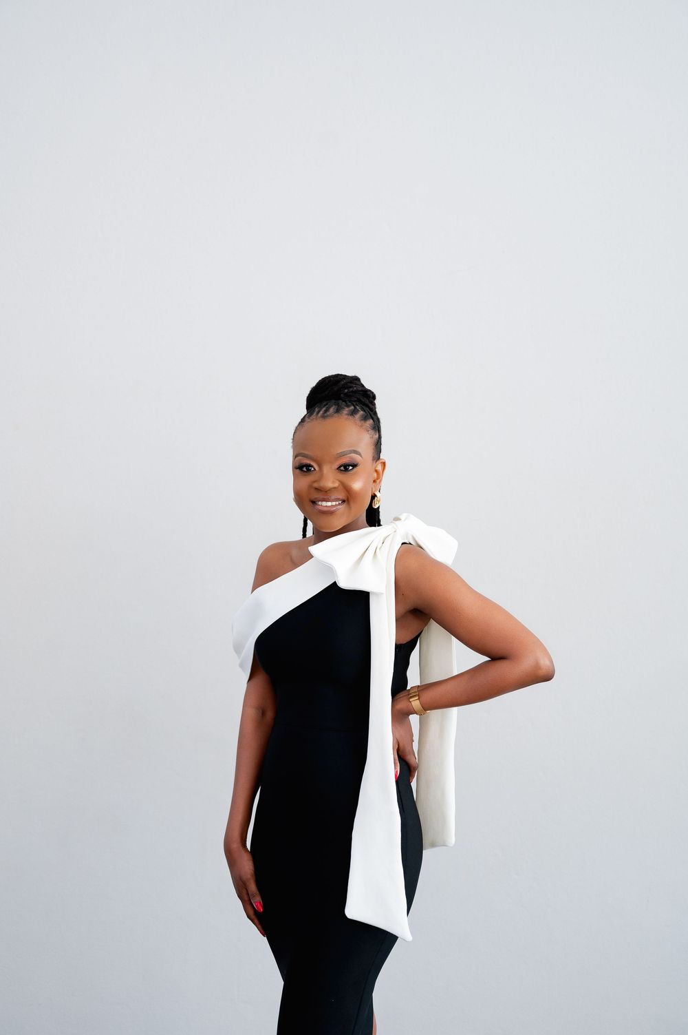 Stylish portrait against white background featuring black top and white fabric draping.