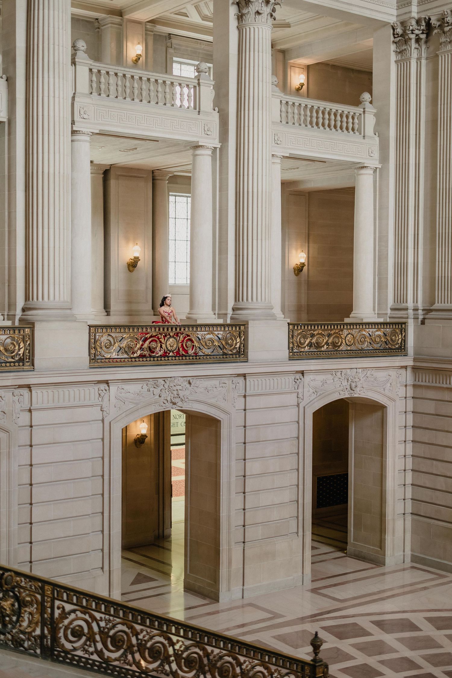 Elegant white marble interior of a grand building with tall columns and ornate gold-accented balustrades and staircases.