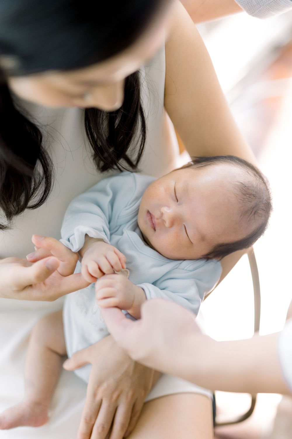 A peaceful scene of a caregiver gently feeding a sleeping infant in soft natural lighting.