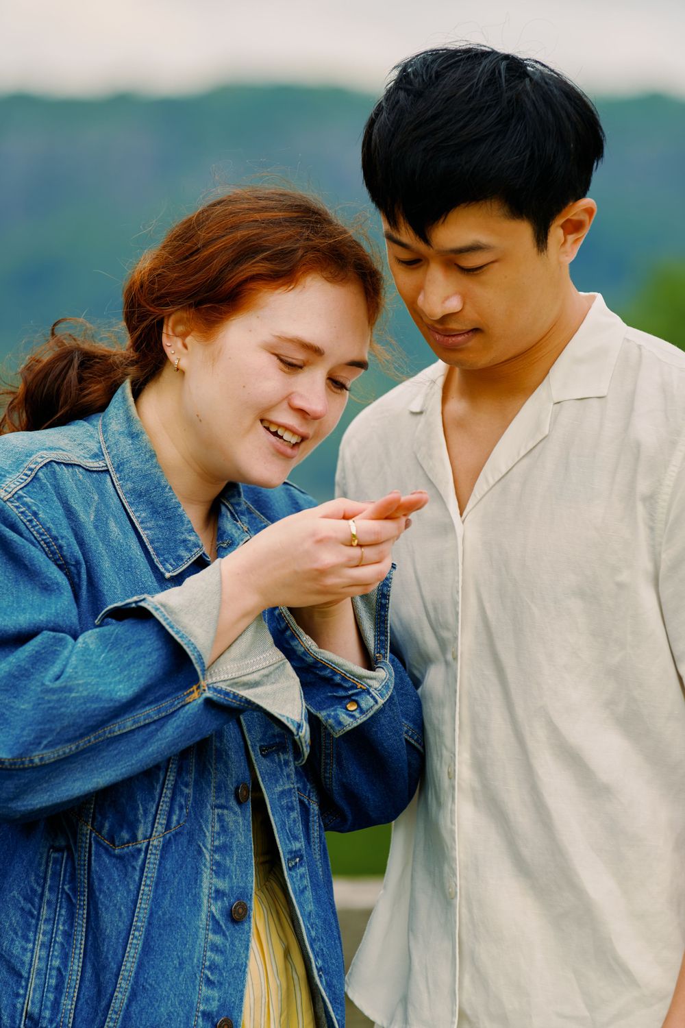 A couple shares a joyful, candid moment together outdoors wearing denim and white clothing. Wave hill garden