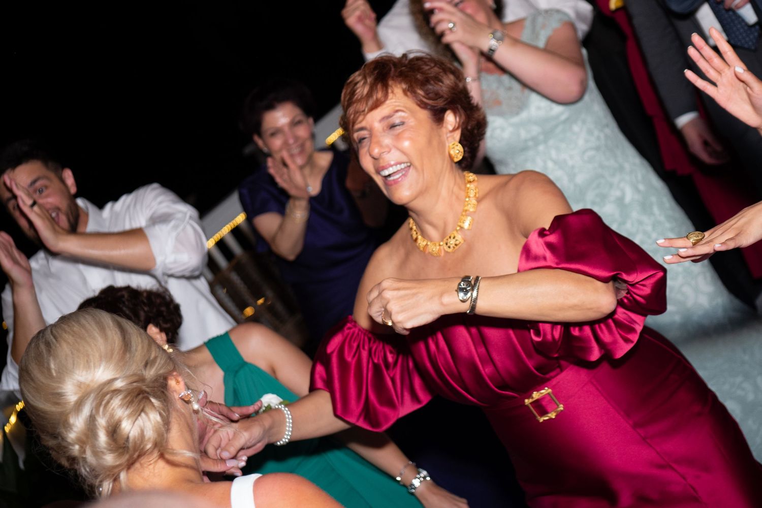 Energetic wedding reception dance party with guests in formal attire.