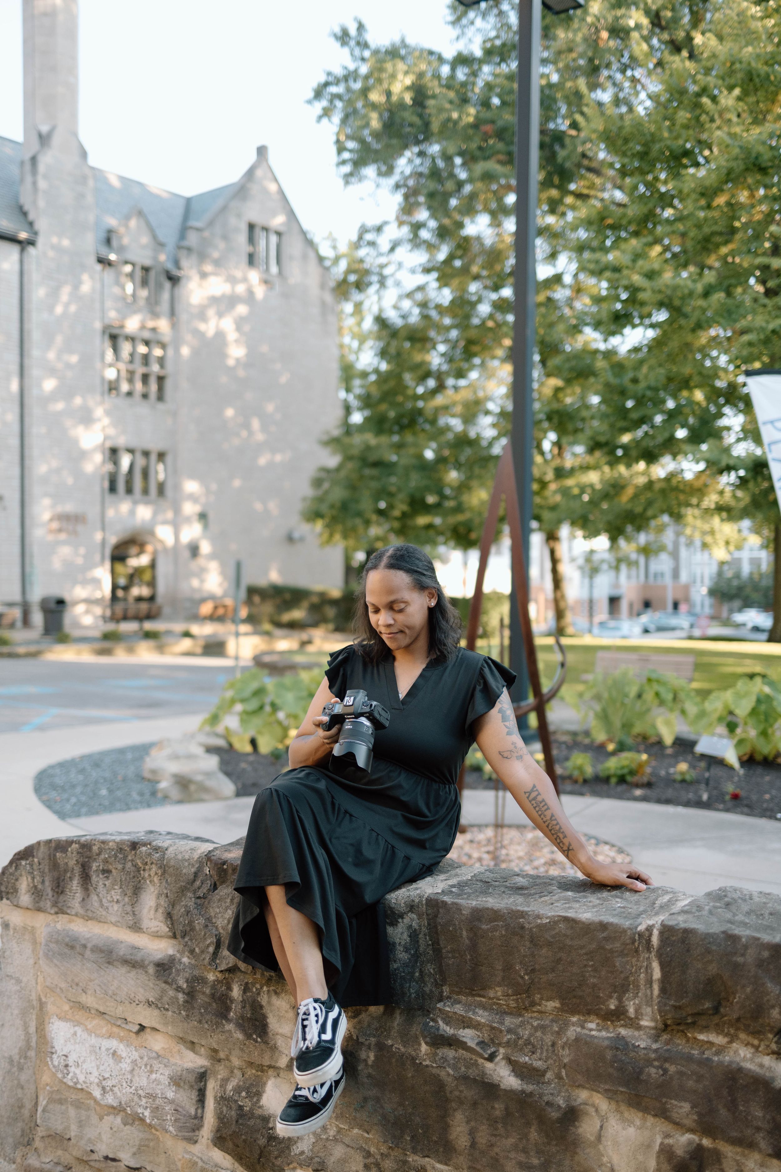 Person poses casually on stone wall during outdoor portrait session.