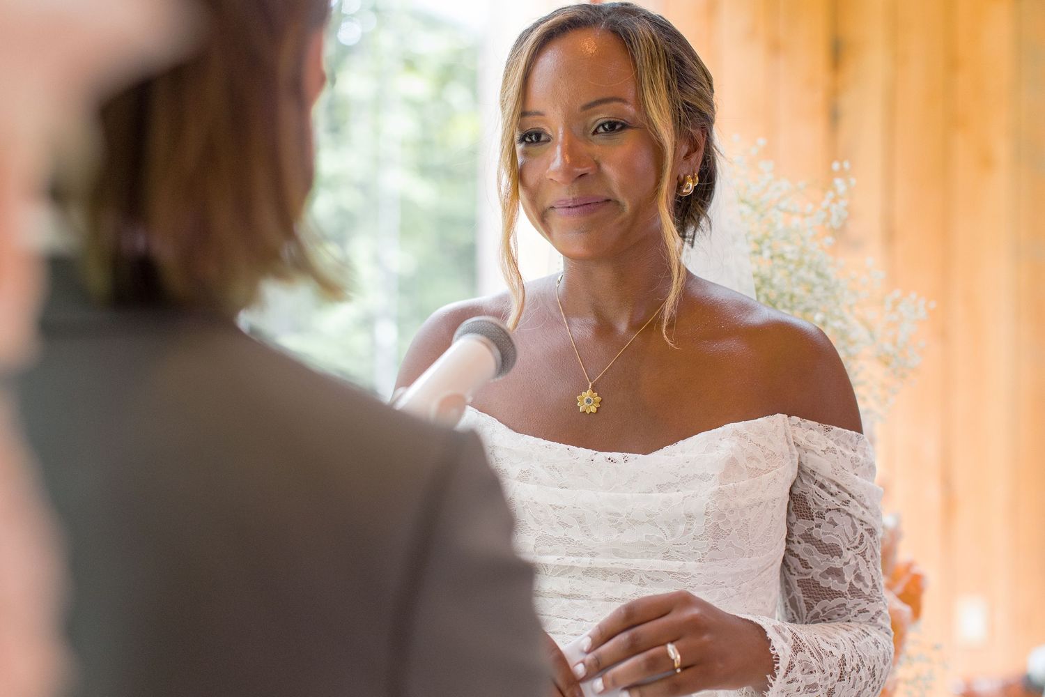 A bride looks stunning in a white lace dress and tiara while getting ready for her wedding day.