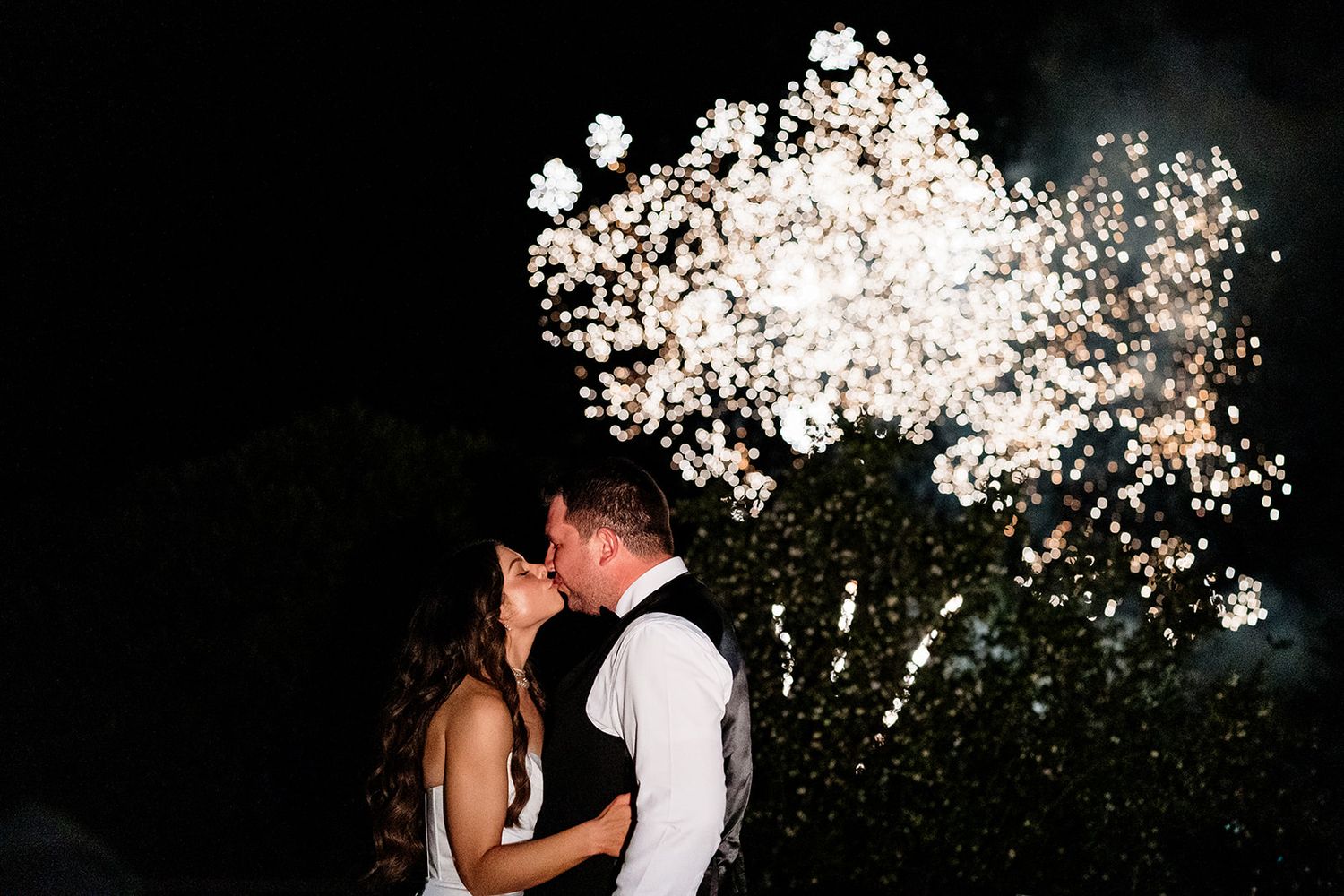 Couple shares romantic dance embrace on outdoor dance floor with fireworks in background at The Dunloe Hotel and Garden