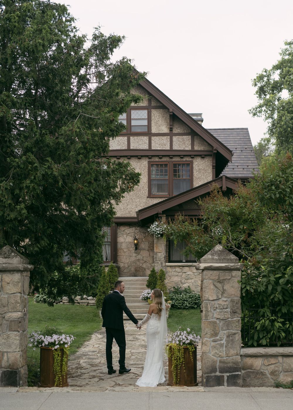 A stone mansion serves as an elegant backdrop for an outdoor wedding ceremony.