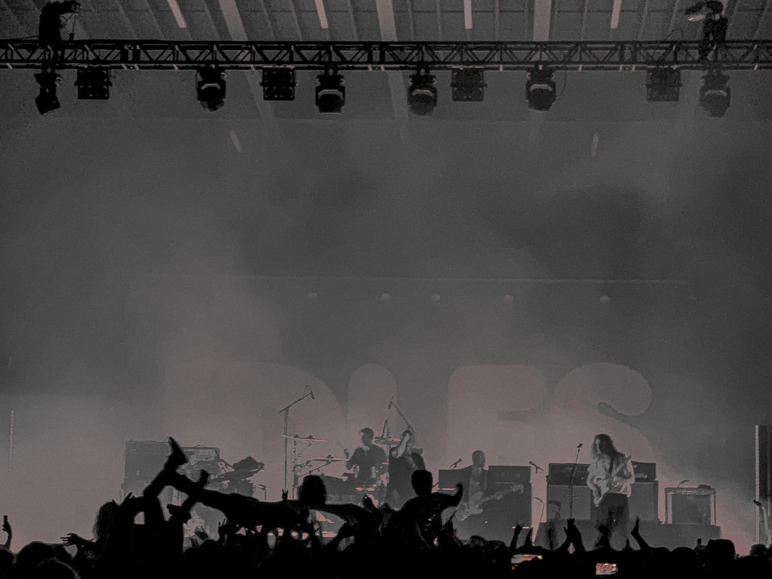 Concert crowd silhouettes stand against bright stage lights during a live music performance. Asheville NC. Idles band.