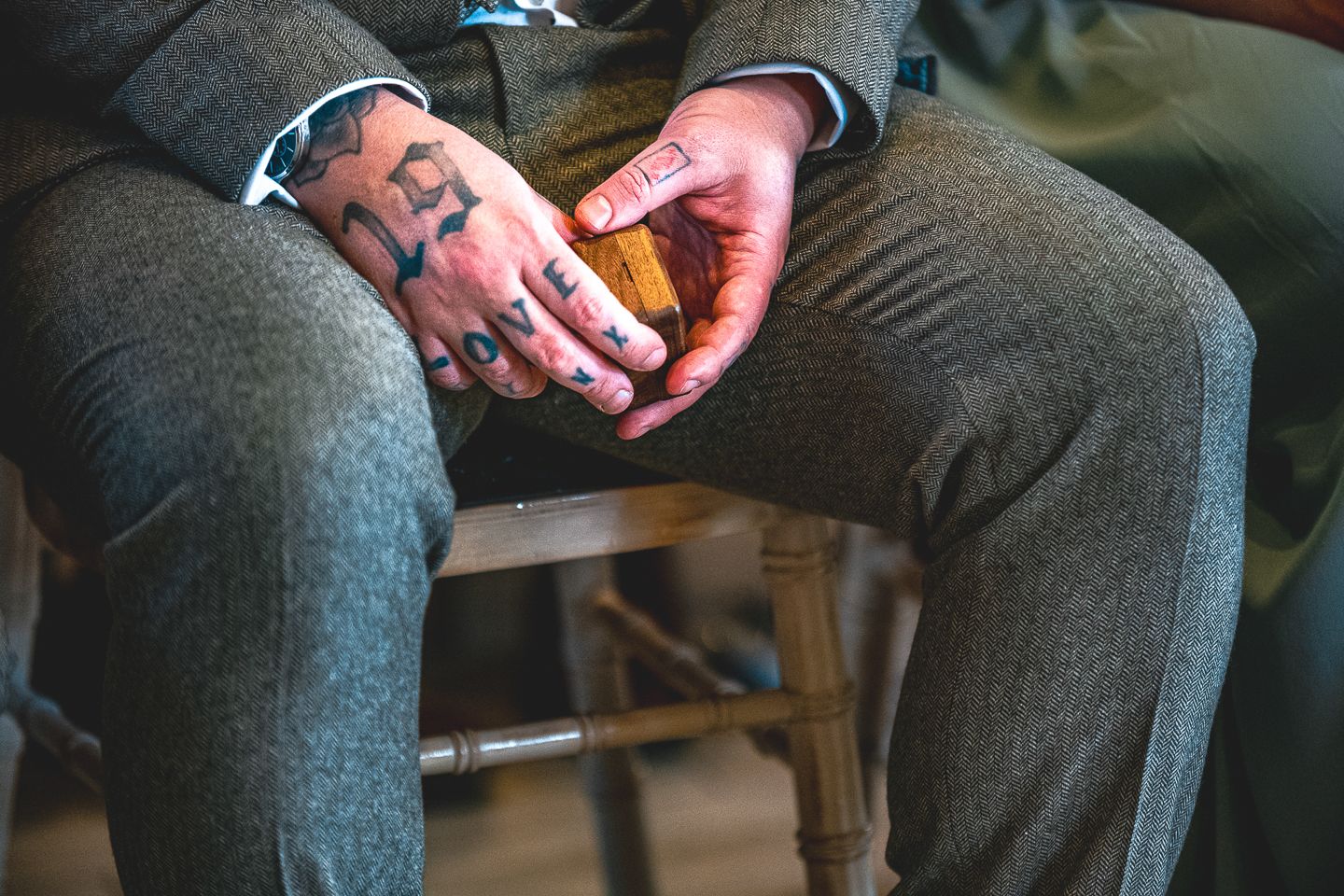 A groomsman with "love" tattooed on his hand, holds rings by Poole, Bournemouth and Dorset wedding photographer "kris the photographer"