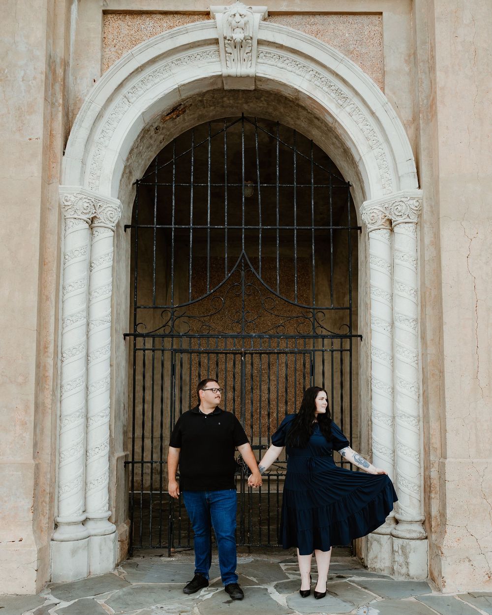 People standing in the arched stone doorway of a historic building with metal gates.