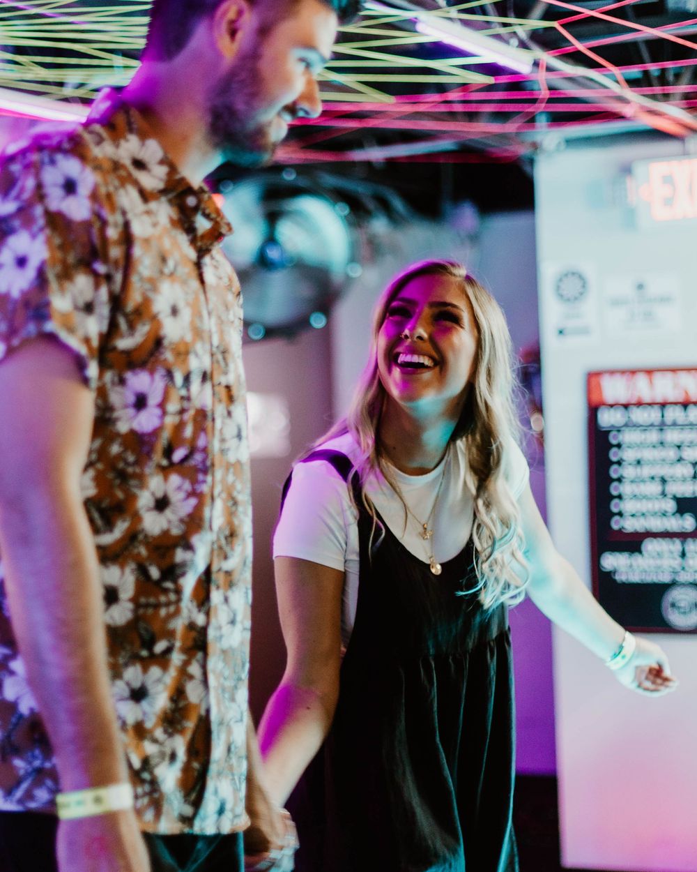 Group of friends enjoying a lively conversation in a venue with colorful purple lighting and modern decor. untraditional engagement photos