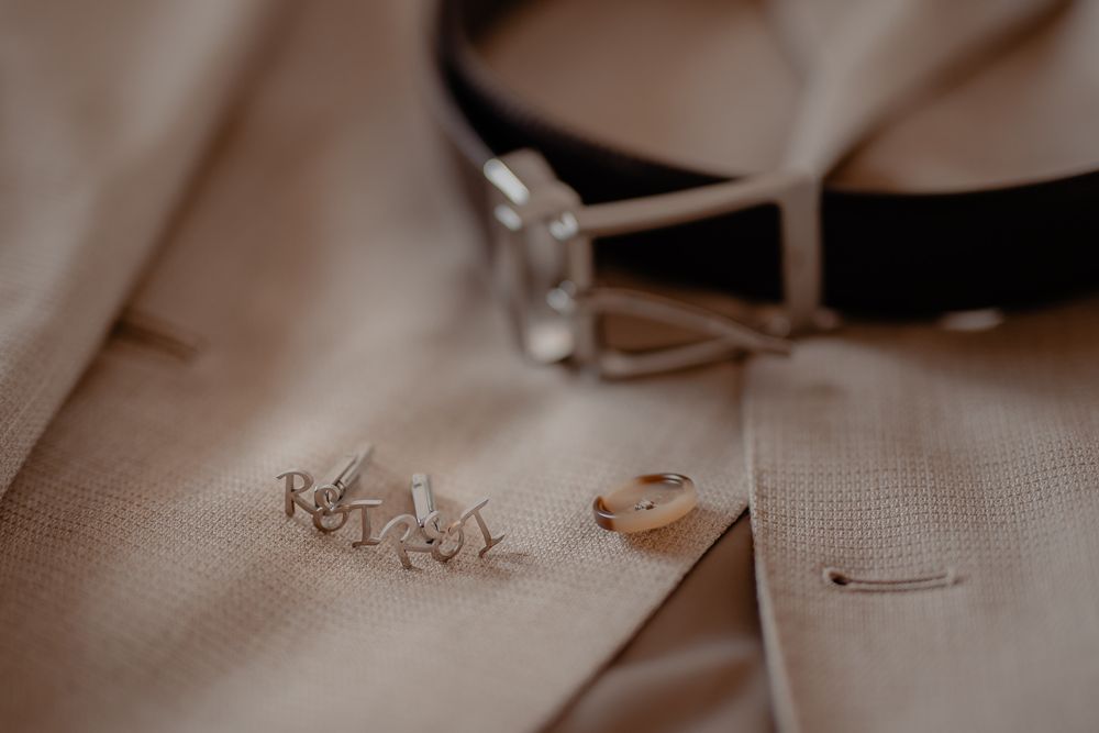 Close-up detail shot of formal attire fabric and accessories in muted tones.