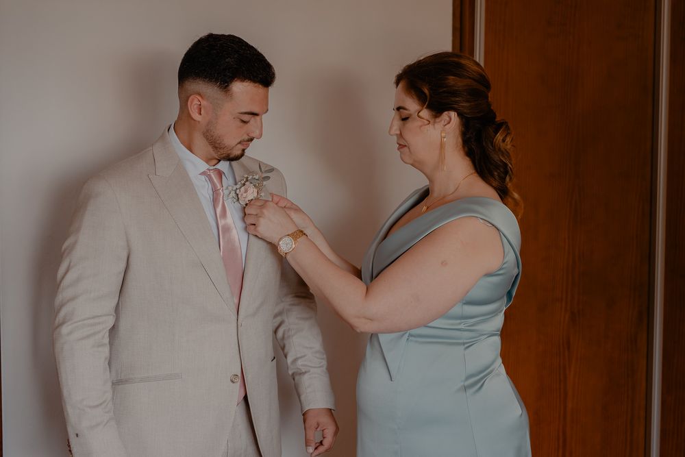 Intimate getting-ready moment between wedding party members in soft lighting.