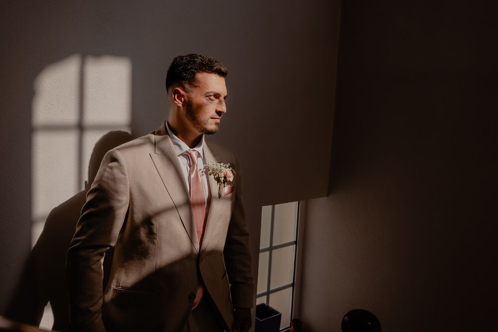 Dramatic portrait in moody lighting with window shadows creating artistic effect.