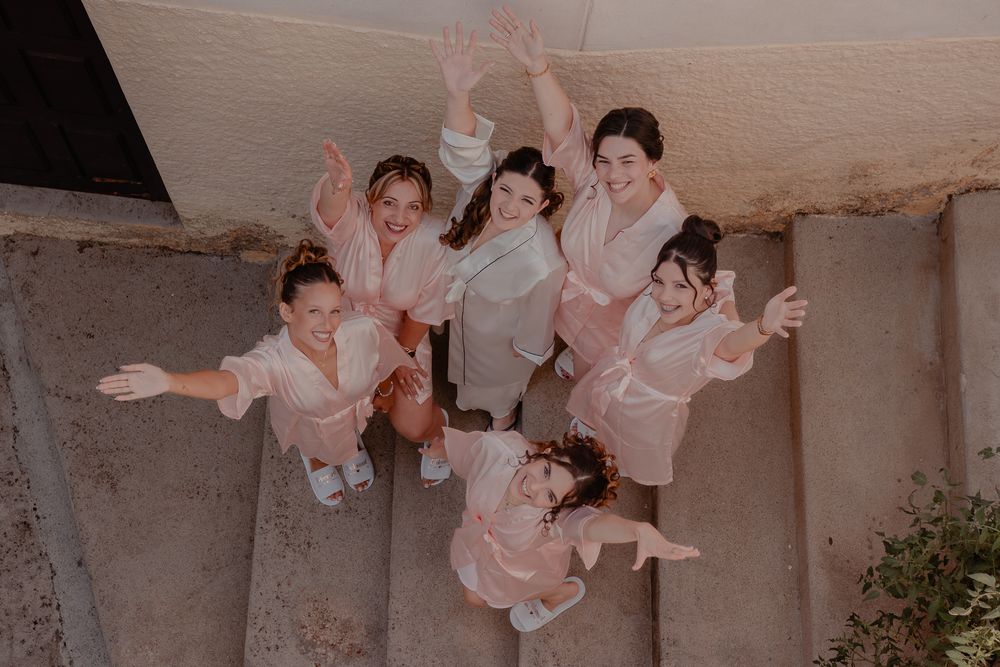 Wedding party members in white robes share joyful moments during pre-ceremony preparations.