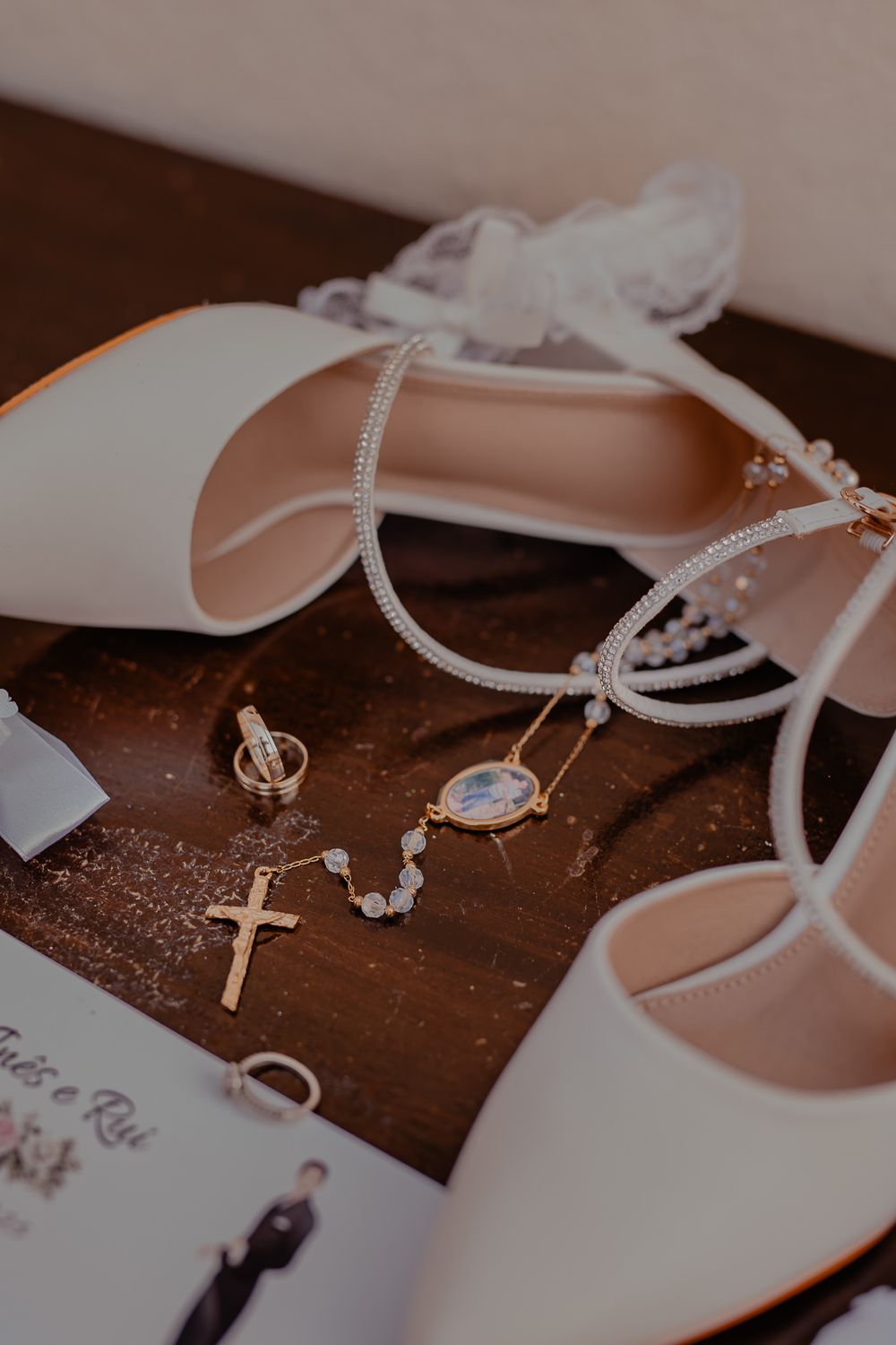 Wedding accessories including white shoes and delicate jewelry on wooden surface.