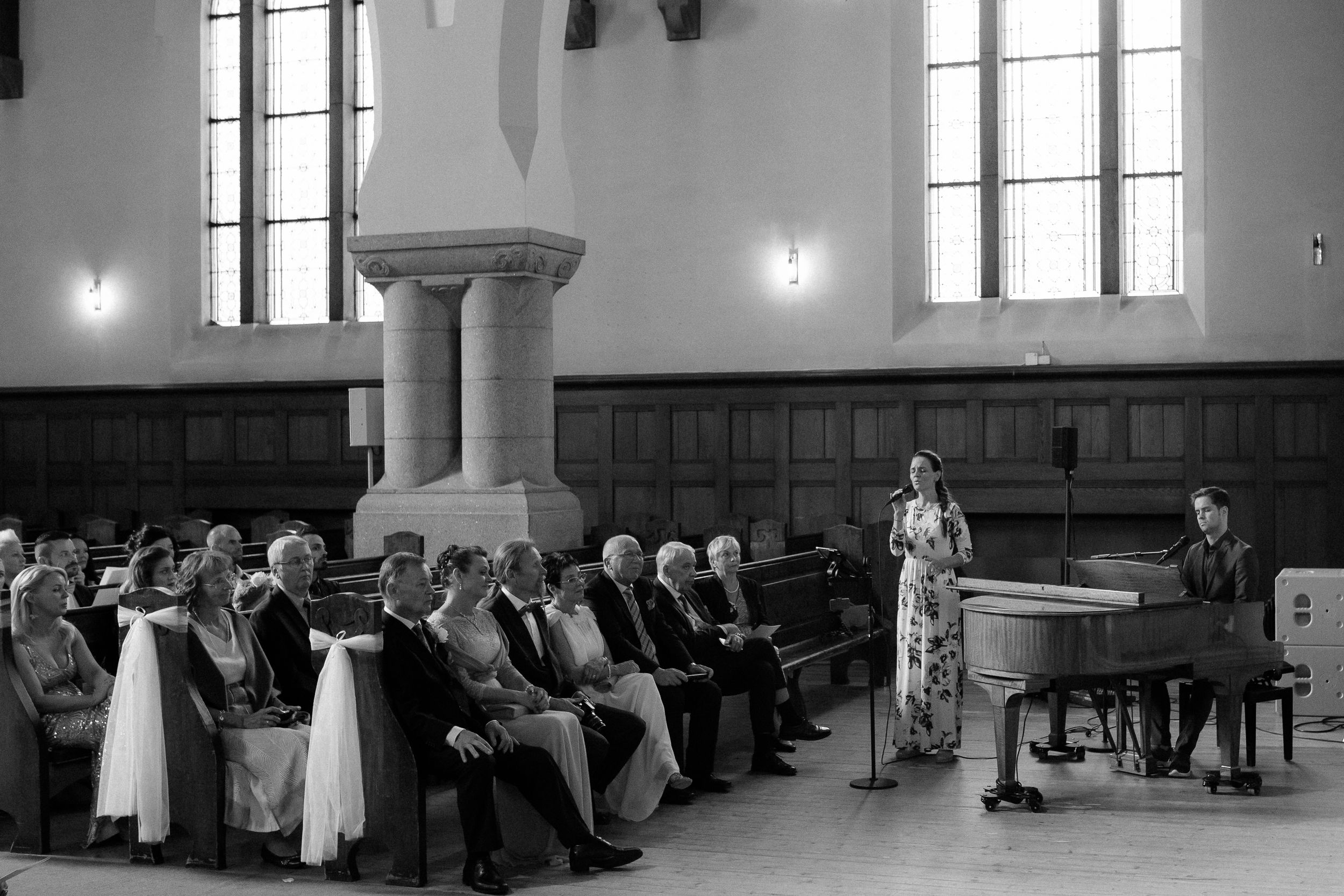 Elegant wedding ceremony in a grand church interior with arched windows and stone columns.