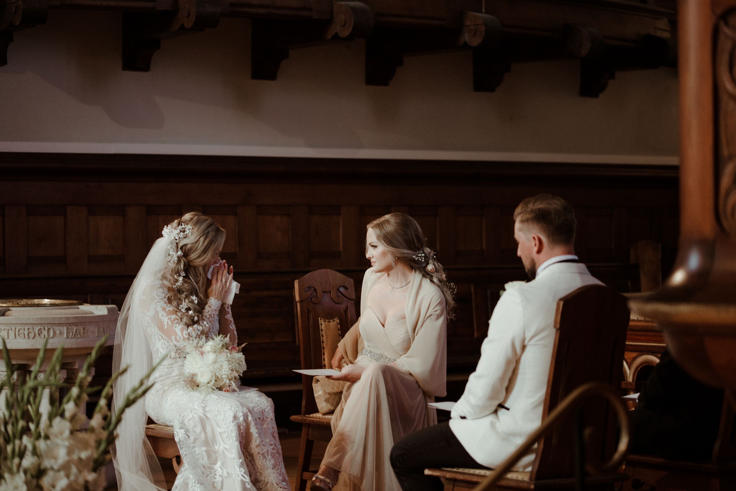 Intimate indoor wedding ceremony with rustic wooden beam ceiling and warm lighting.