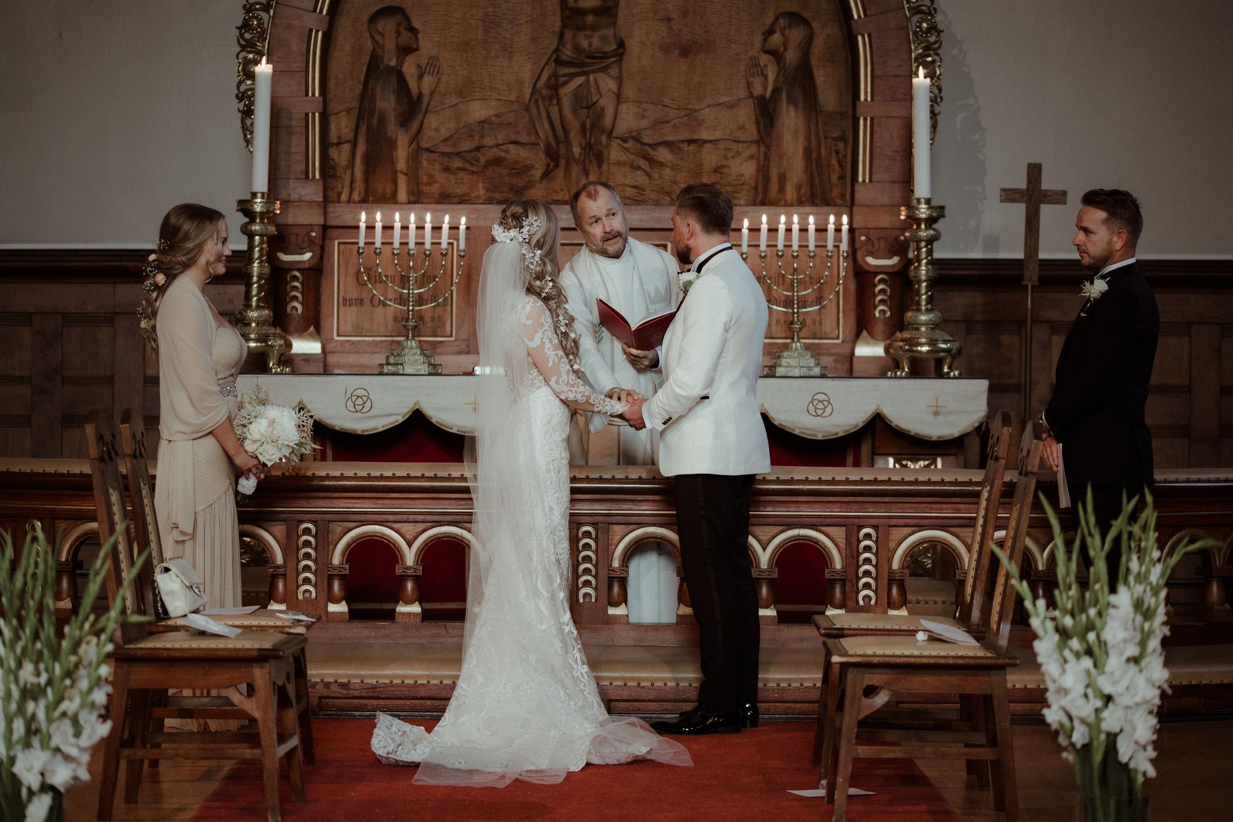 Wedding ceremony taking place in a traditional church sanctuary with stone walls and stained glass windows.