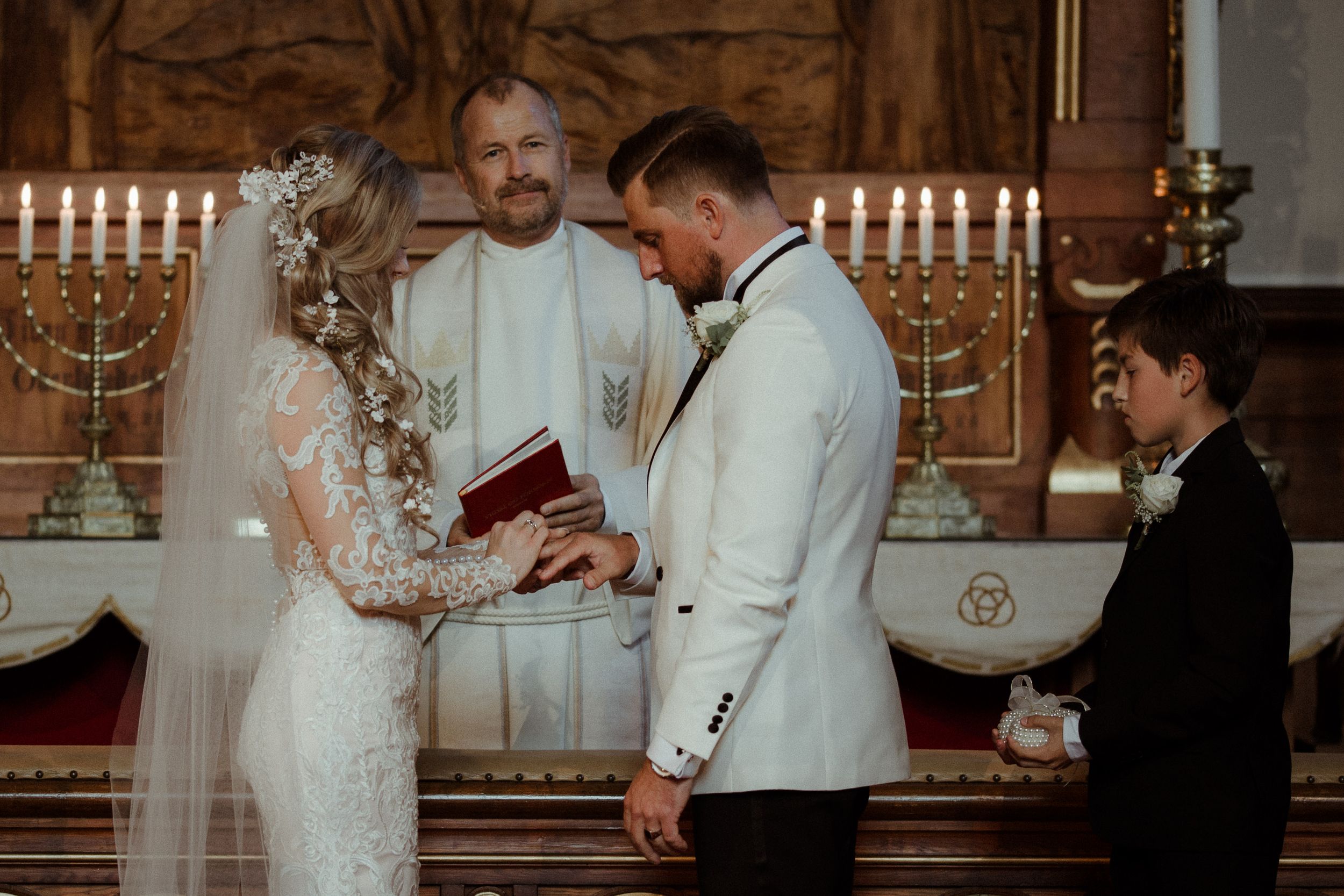 Candlelit wedding ceremony in traditional church setting with ornate decorations.