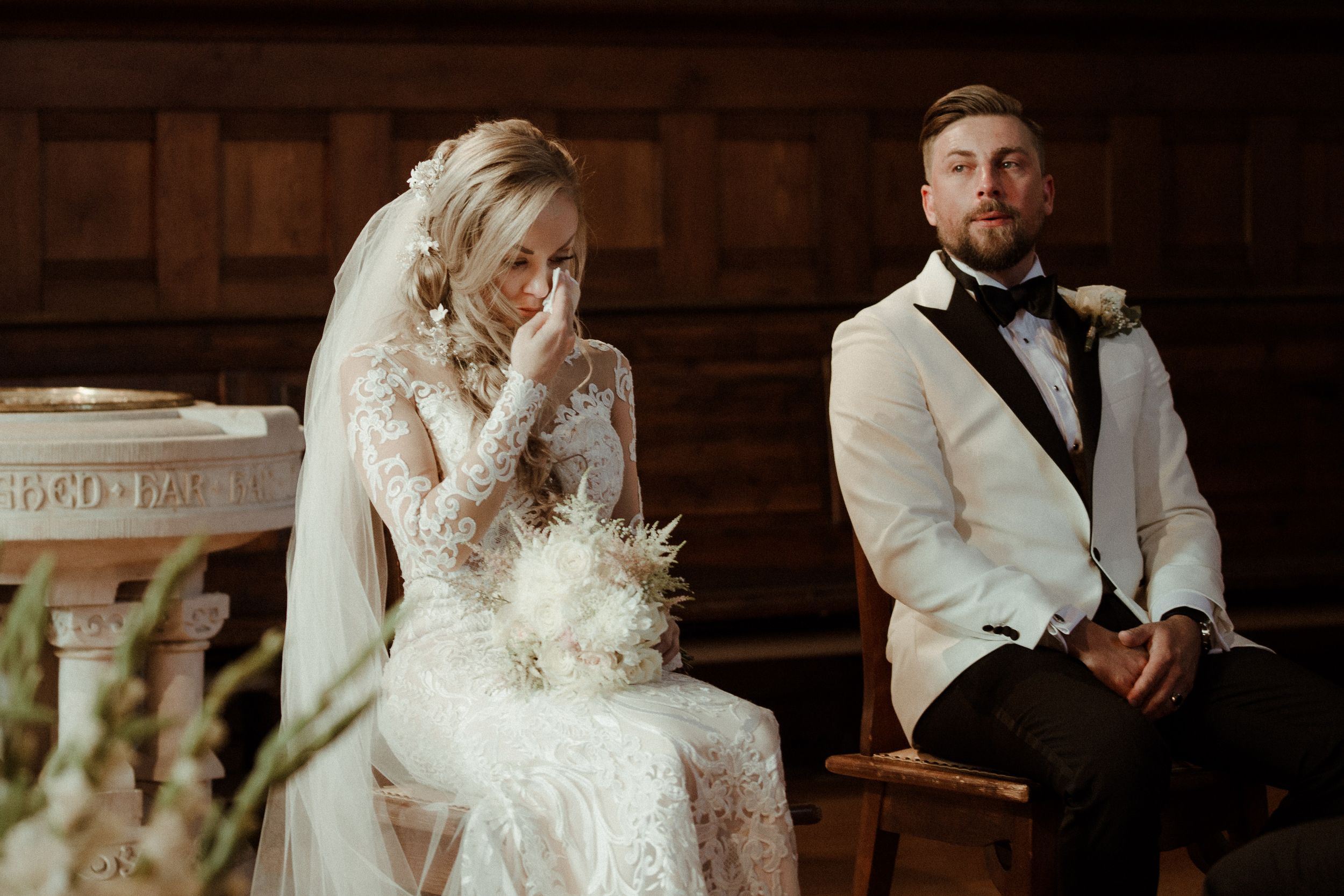 Romantic wedding portrait session in a dimly lit room with wooden paneled walls.