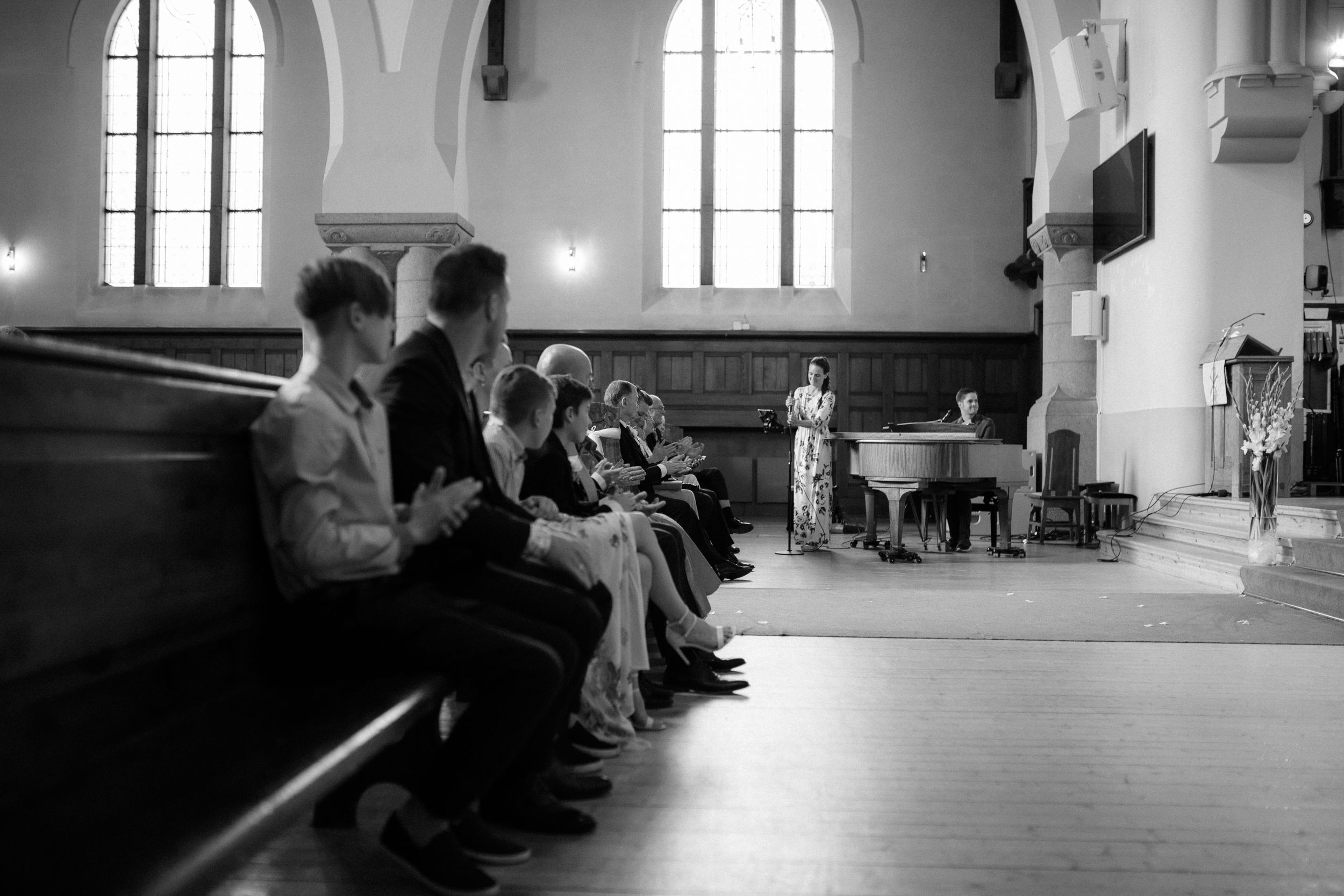 Church interior with dramatic lighting through large arched windows during a wedding ceremony.