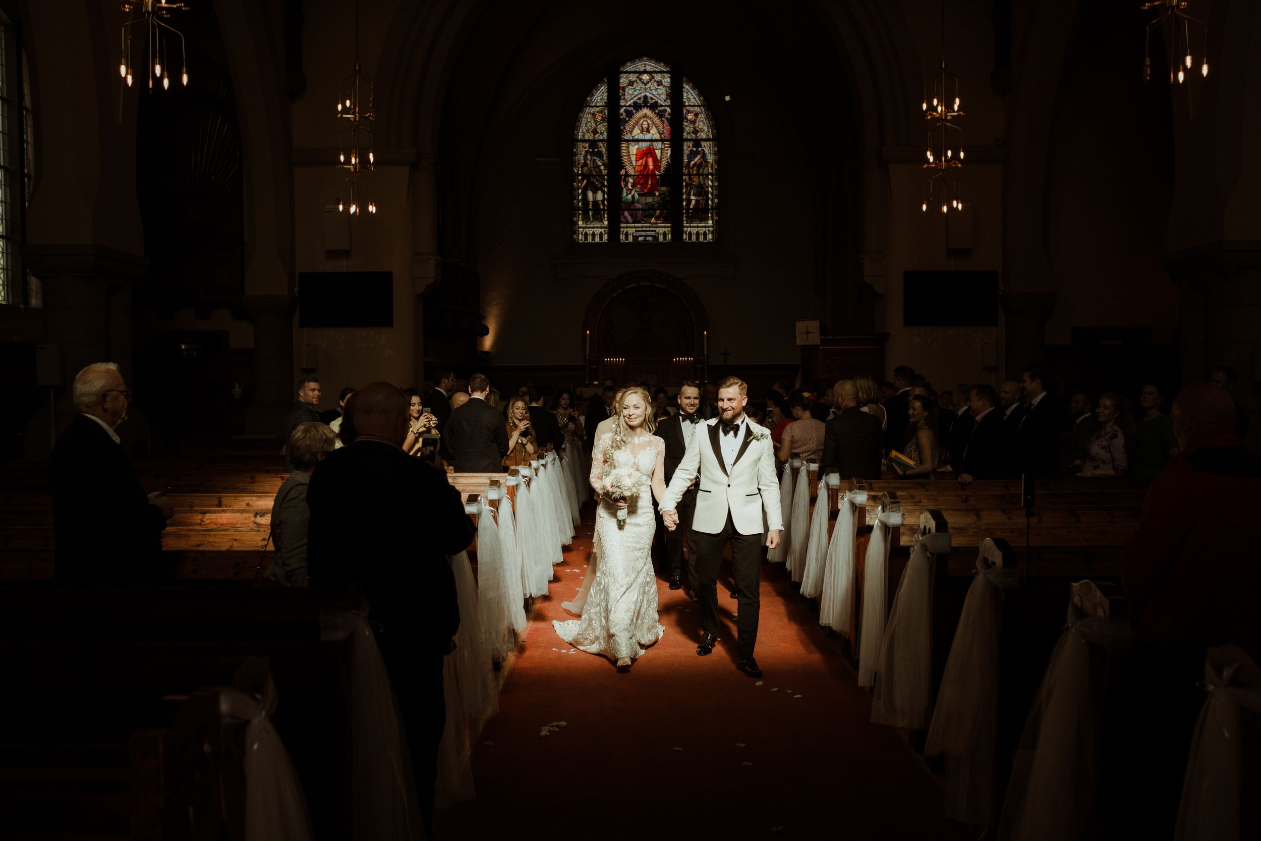 A candlelit church ceremony with dramatic lighting and white chair decorations.