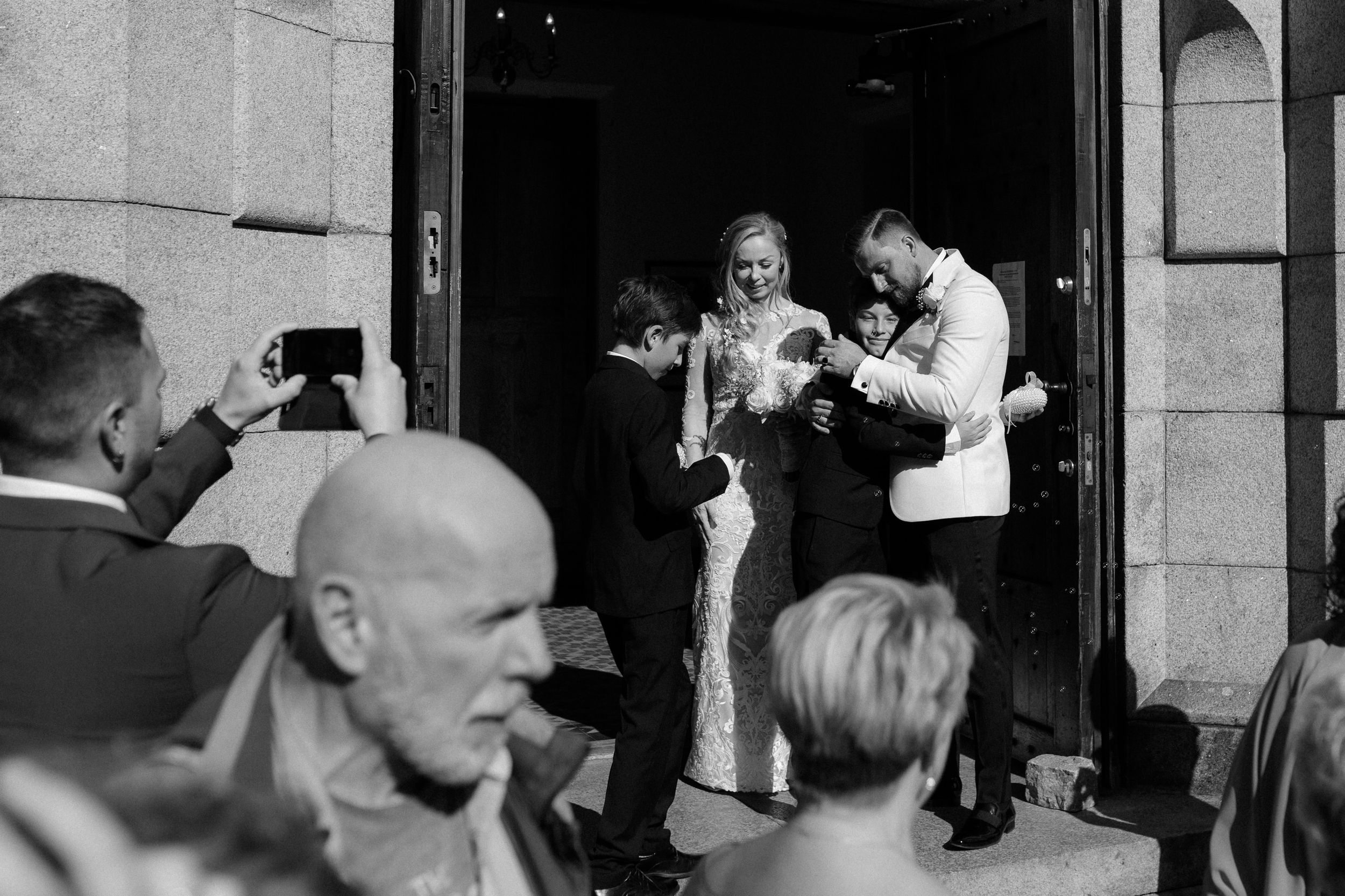 Photographers capture a special moment at the church entrance during a wedding celebration.