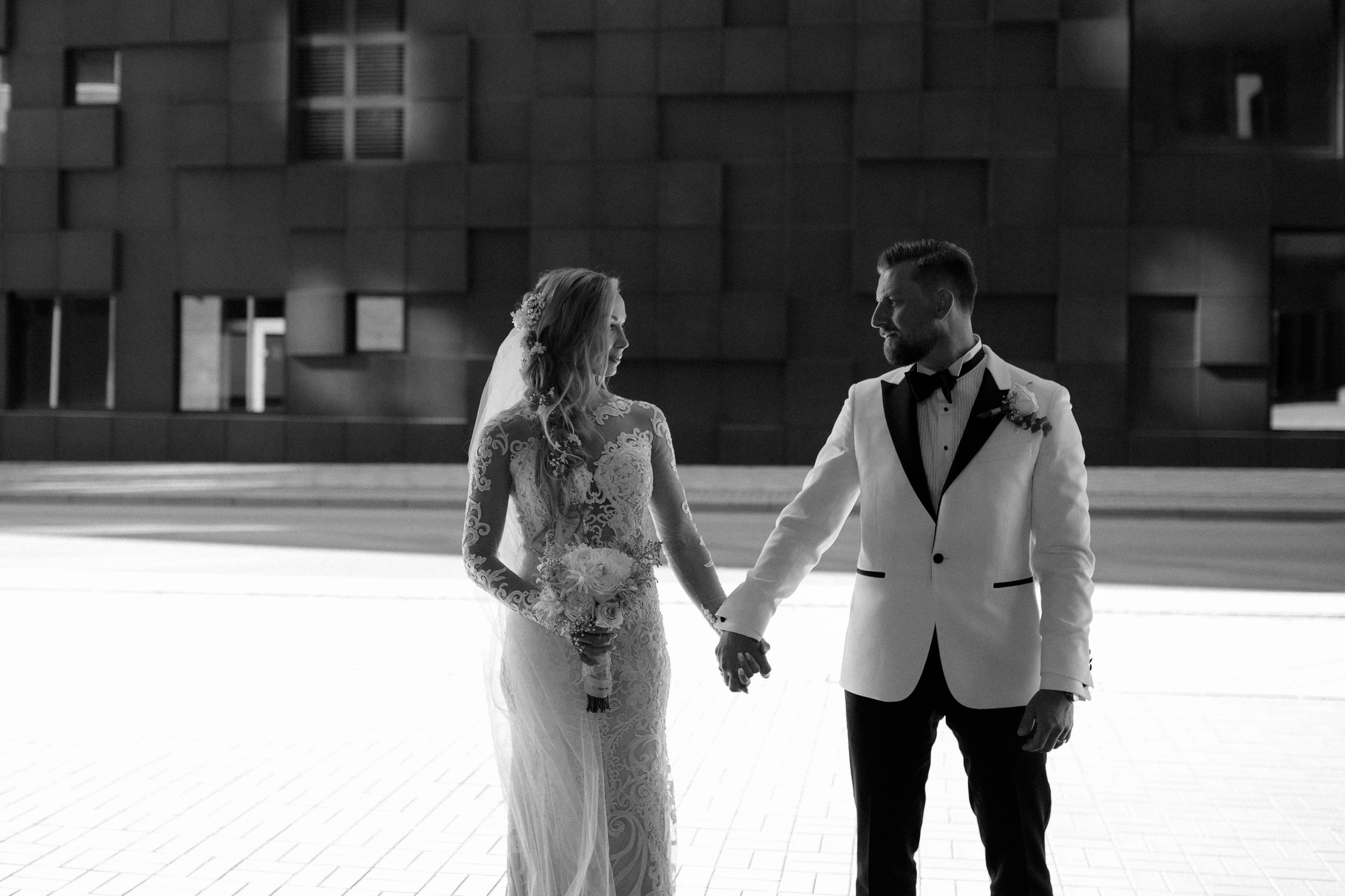 Romantic black and white wedding scene in an urban setting with modern architecture.