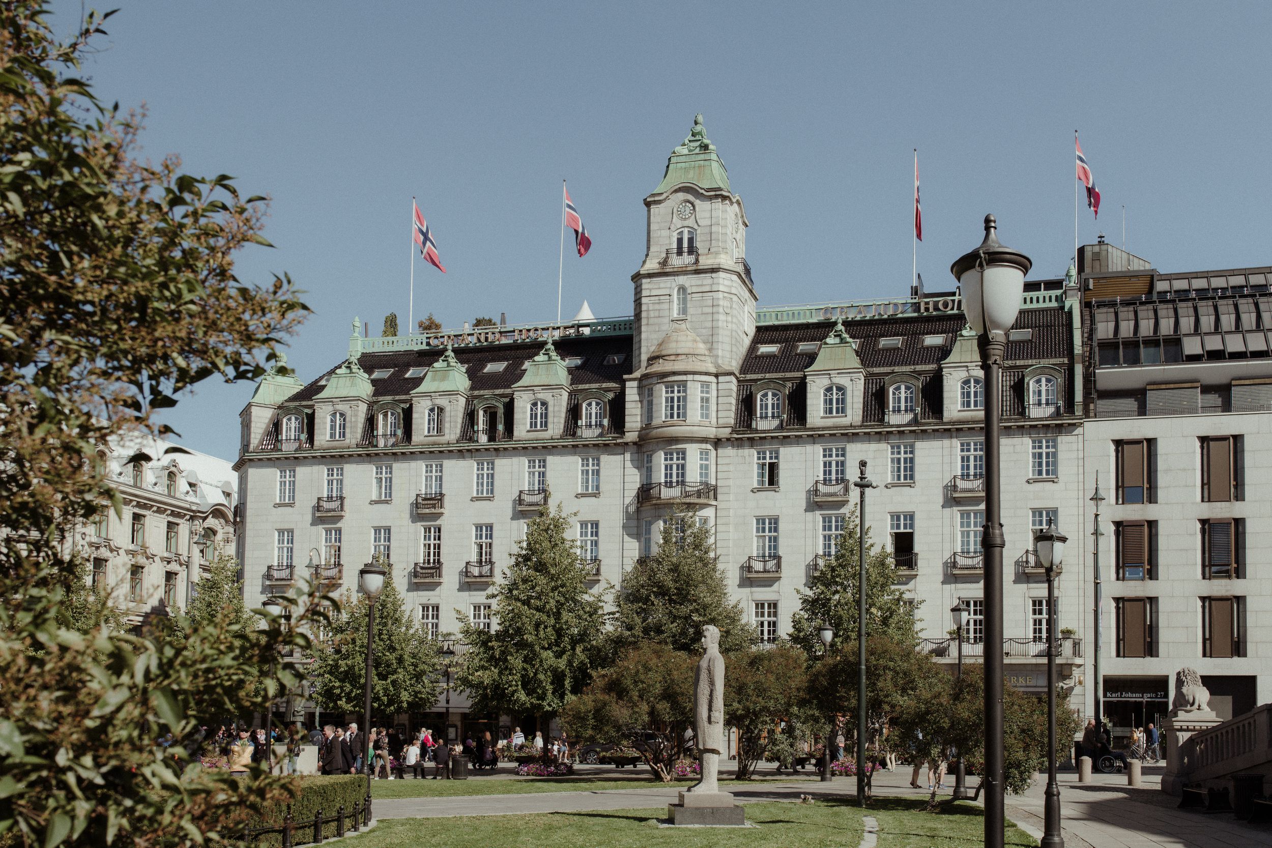 Historic university campus buildings with copper domed towers and Canadian flags flying against blue sky.