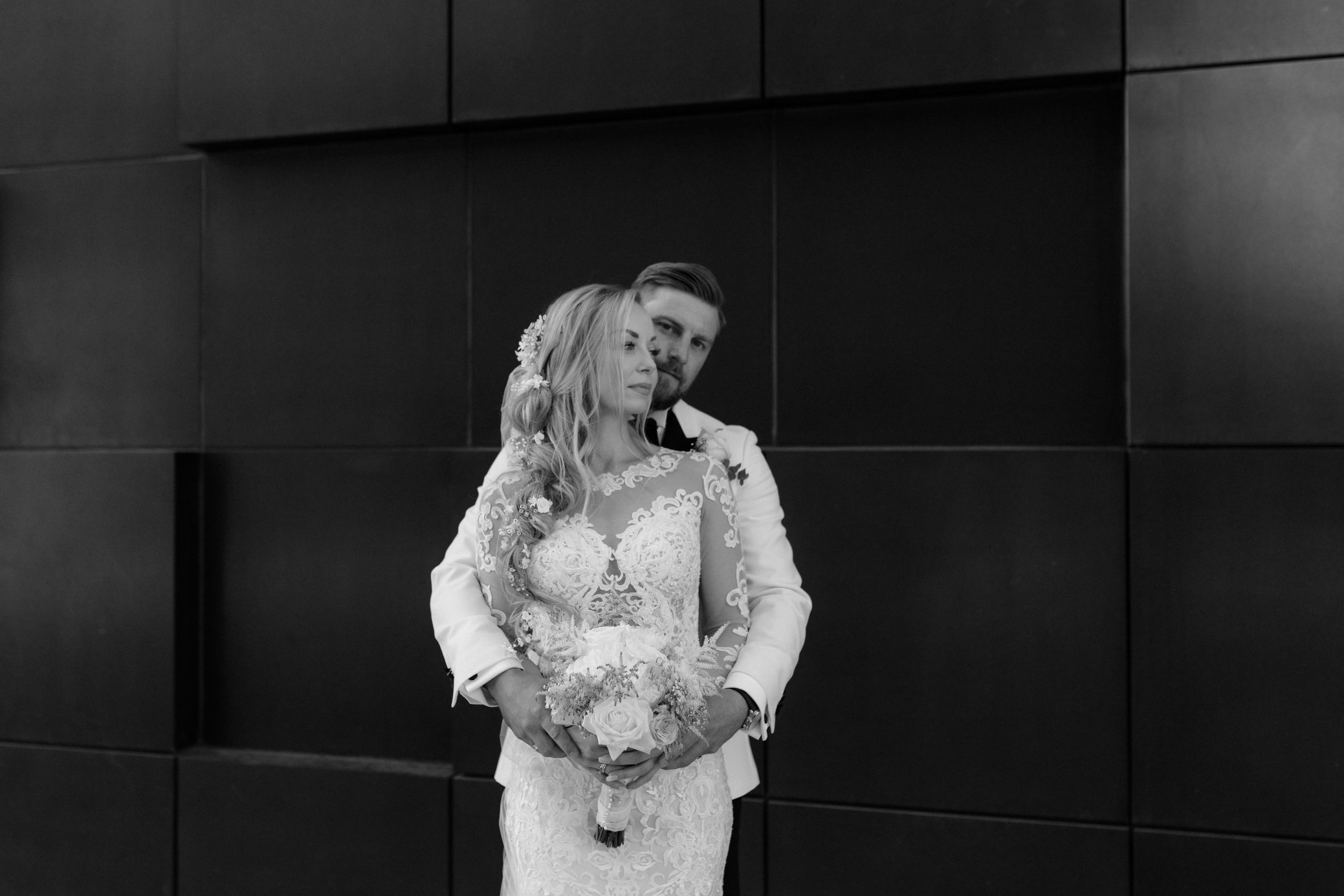Intimate black and white wedding moment captured against a dark modern backdrop.