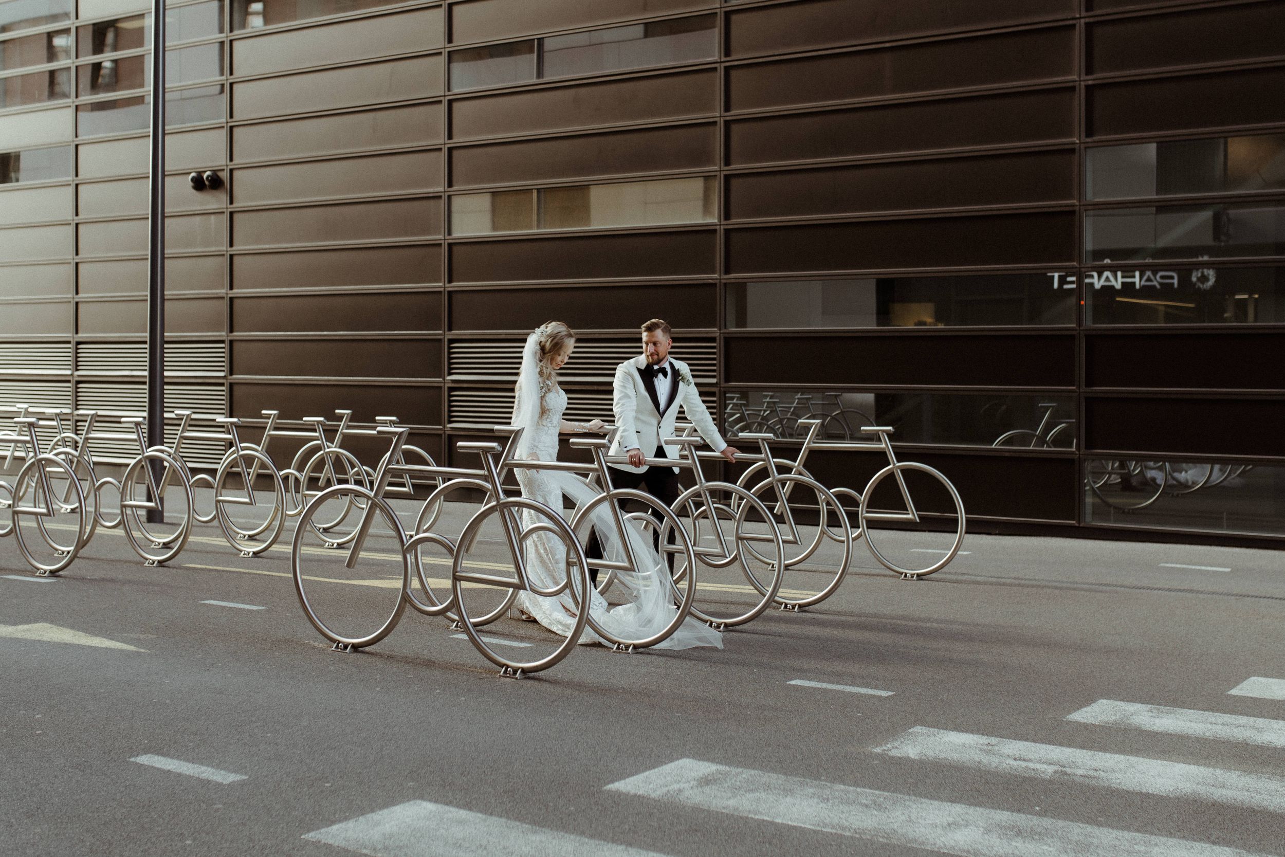 Wedding couple poses with vintage bicycles on an urban street.