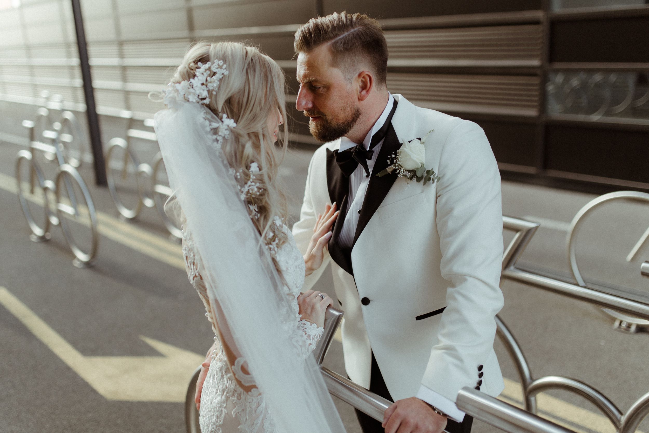 An intimate wedding moment captured in a sunlit urban setting with modern architecture.