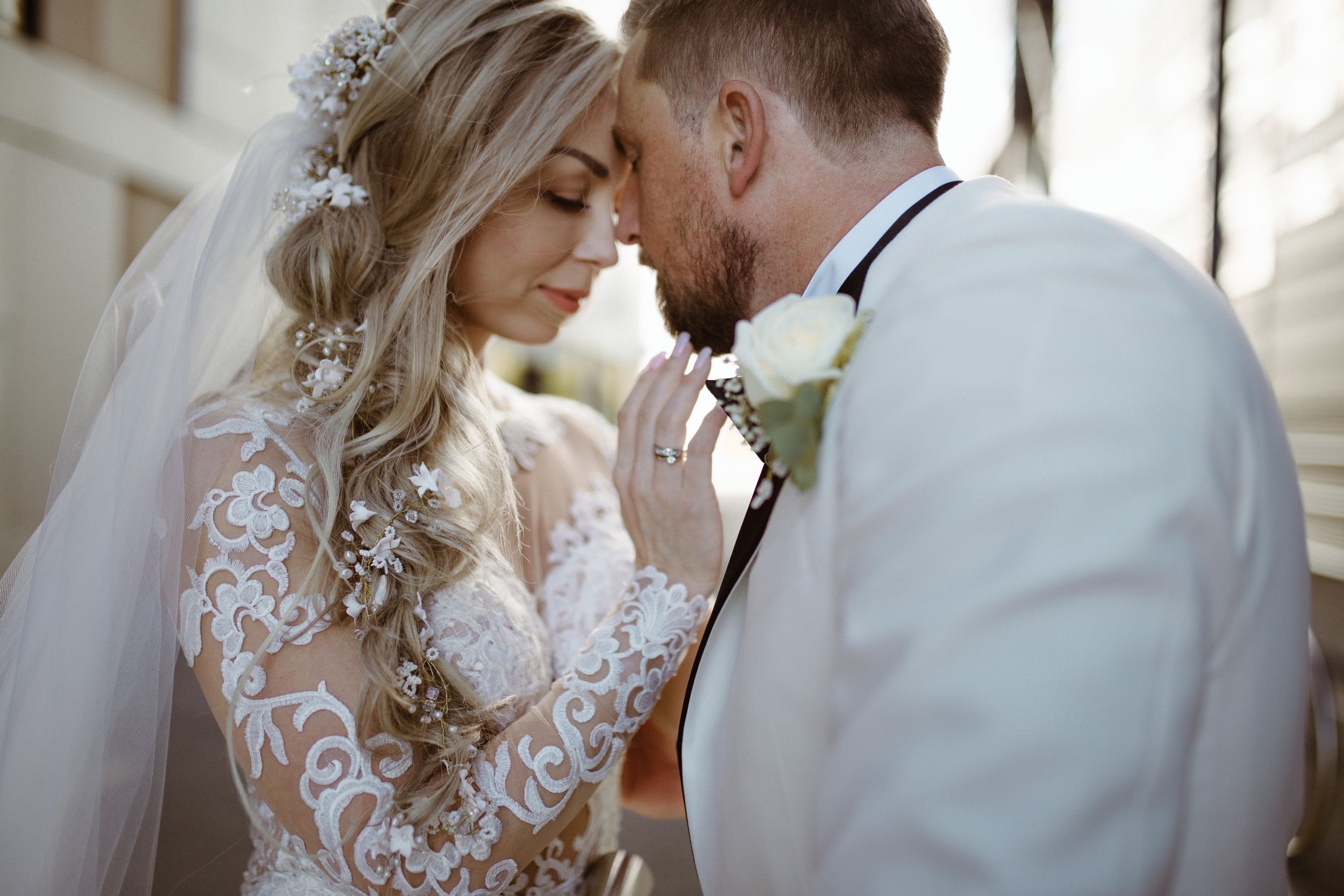 A tender moment shared between newlyweds against a light-filled interior backdrop.