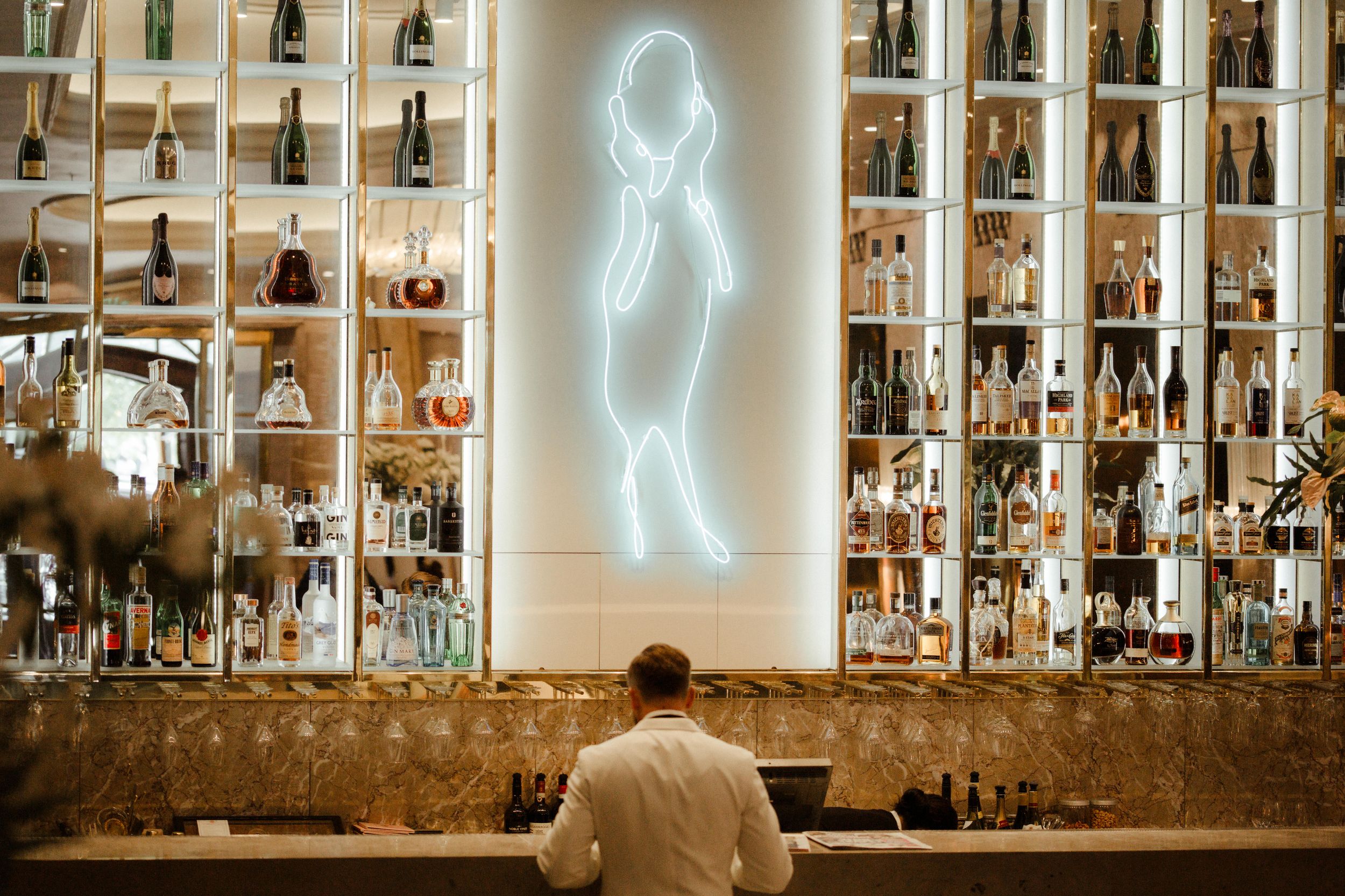 Bar shelves illuminated by neon lightning bolt signs create a dramatic ambiance in an upscale establishment.