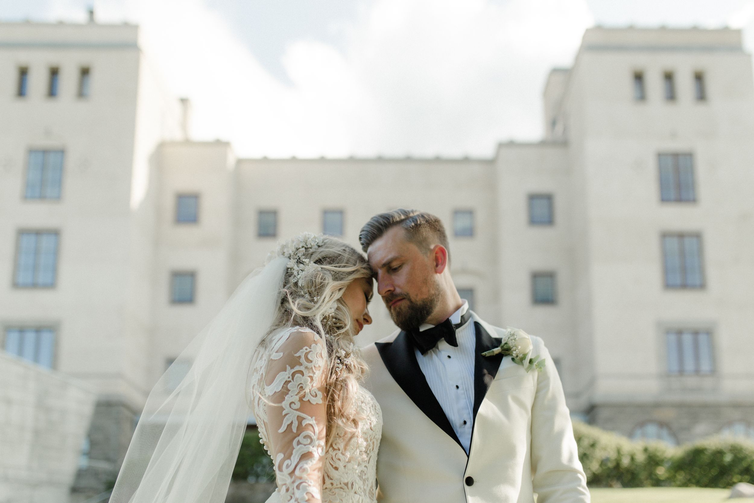 White colonial-style mansion provides stunning backdrop for wedding photography.