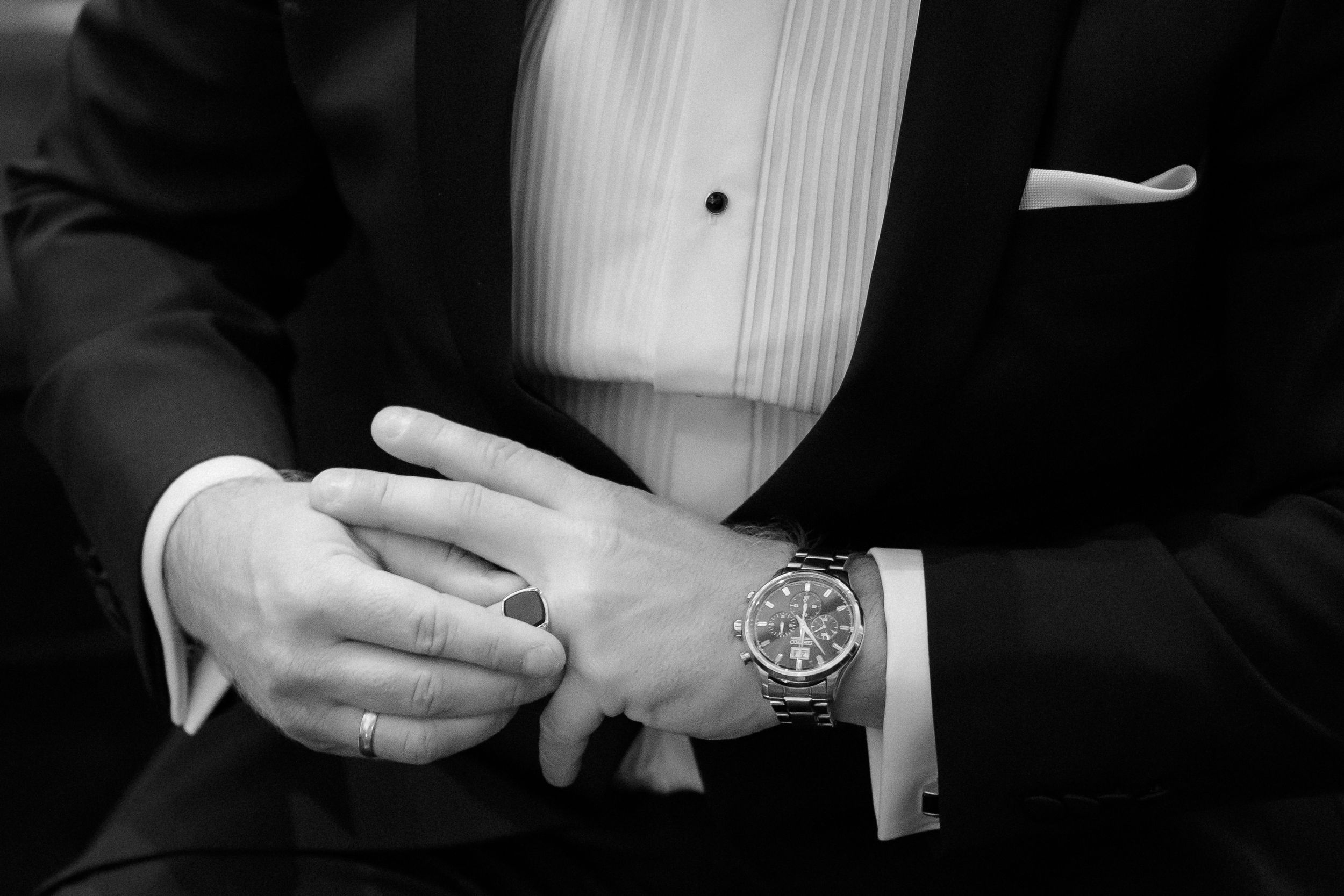 Close-up detail of formal tuxedo shirt and cufflinks in black and white.