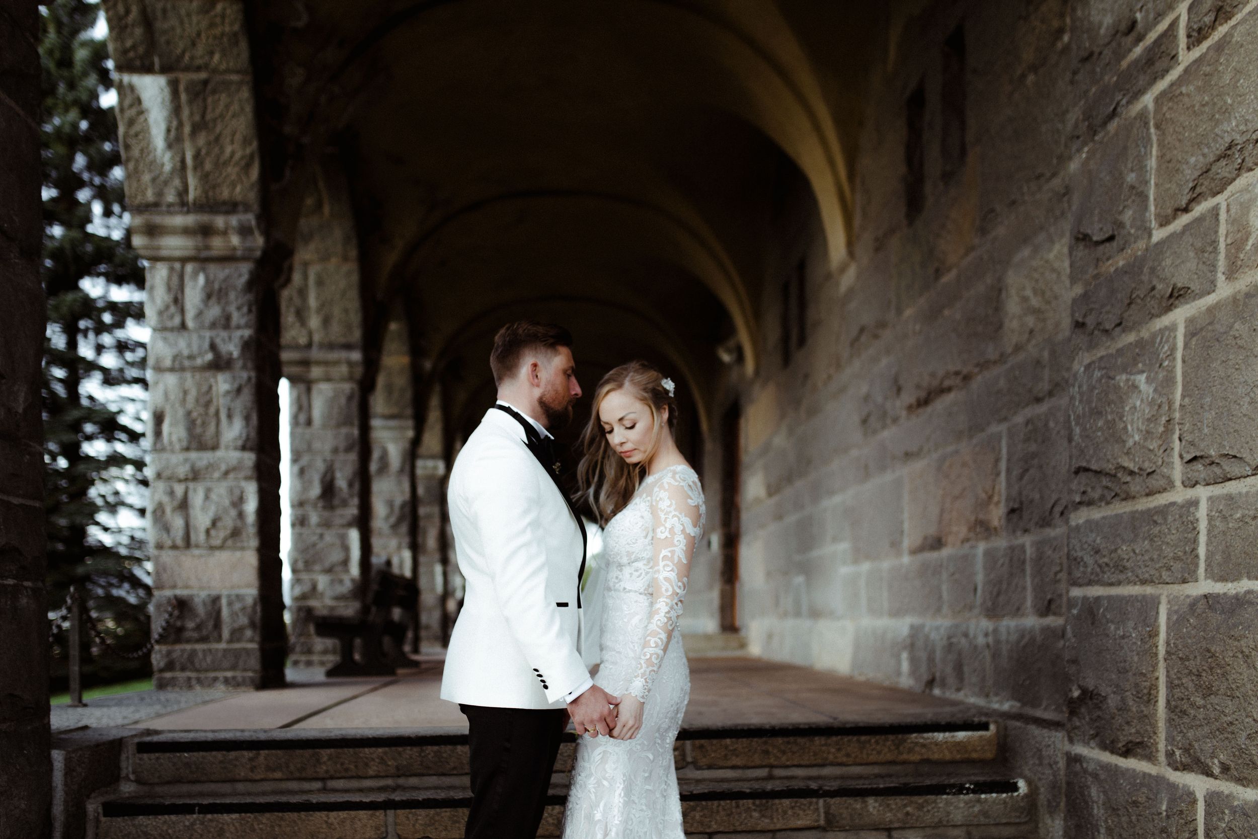 Romantic wedding photos captured in stone archway corridor.