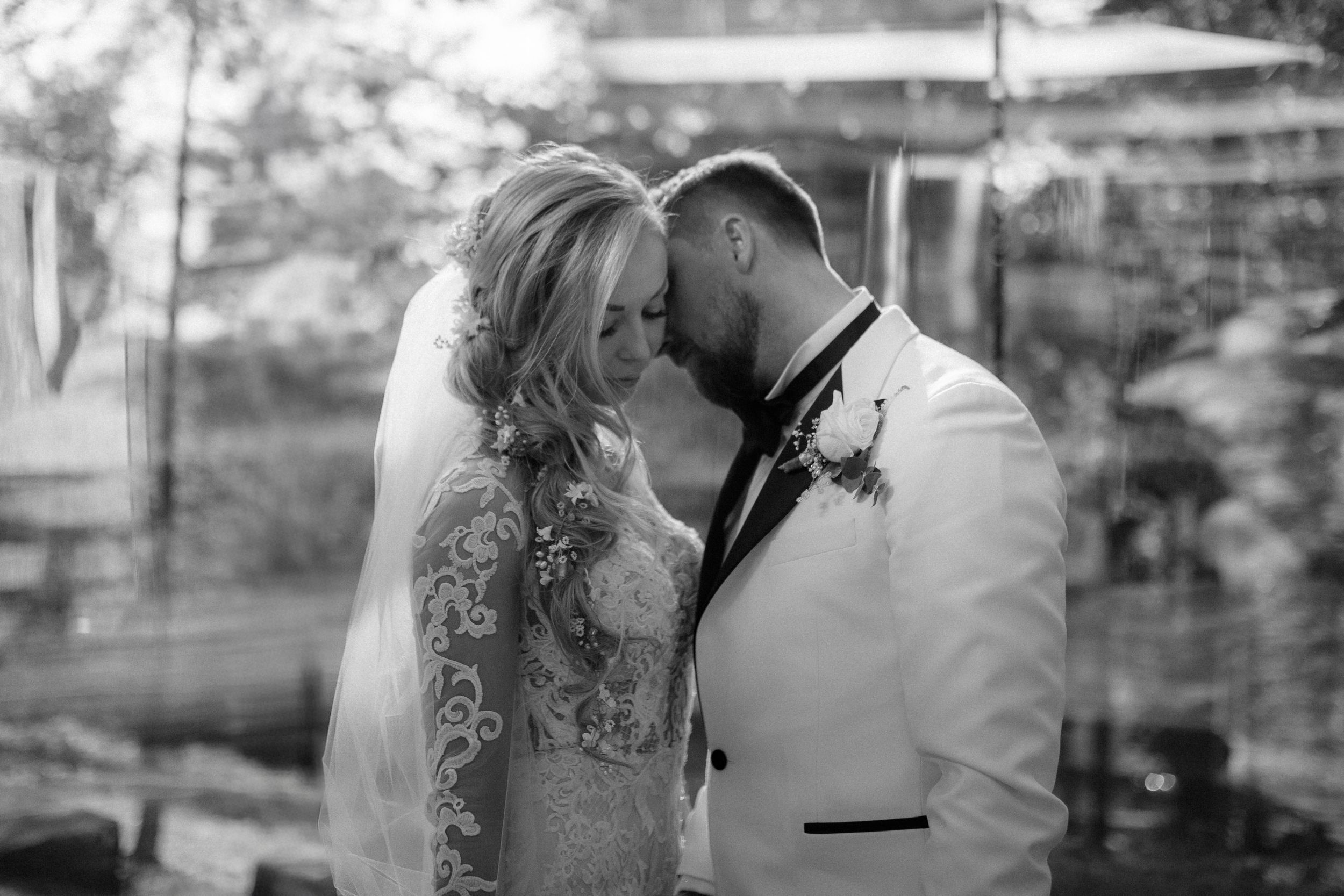 An artistic black and white wedding portrait in an outdoor garden setting.