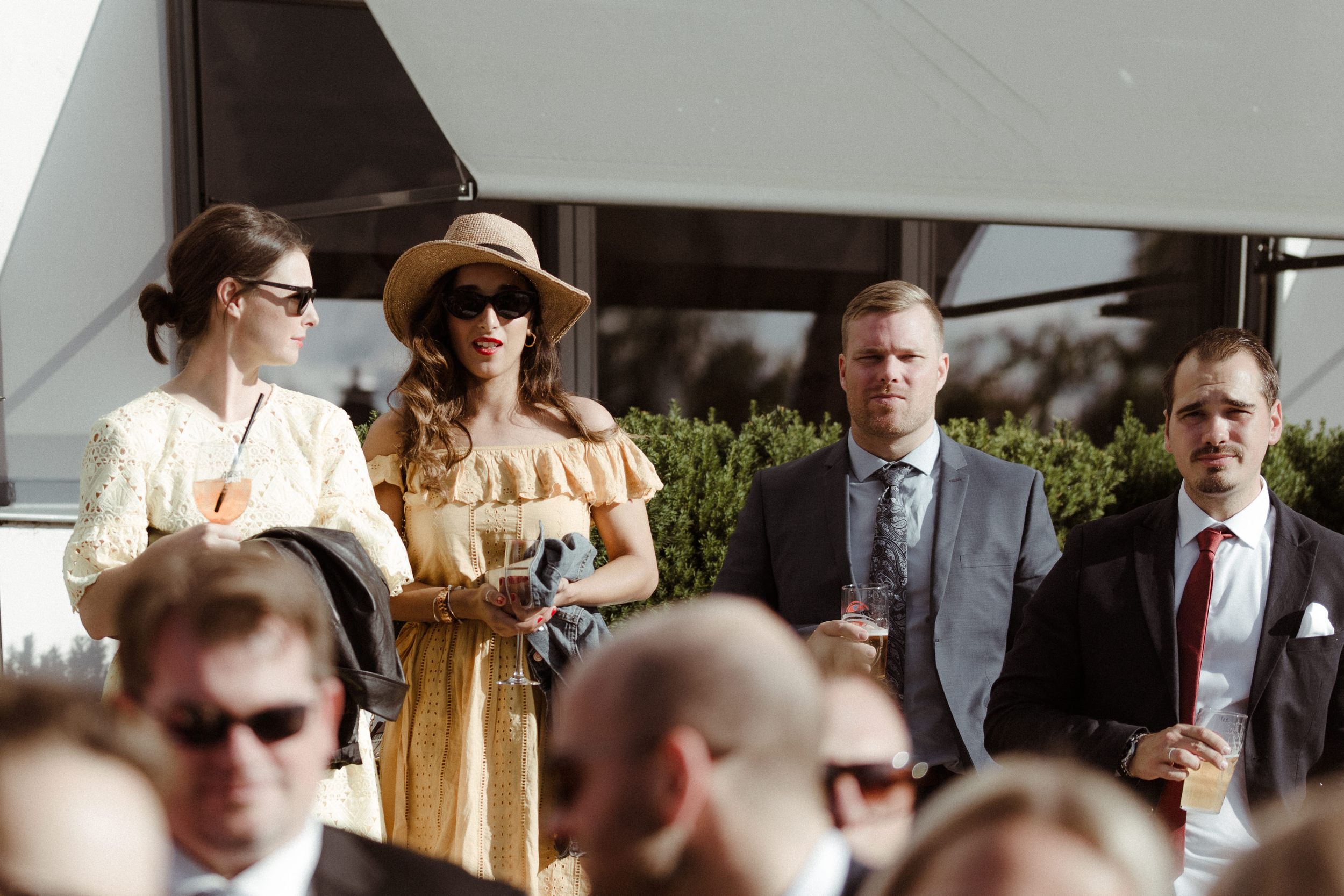 Outdoor wedding reception gathering with guests in formal attire.