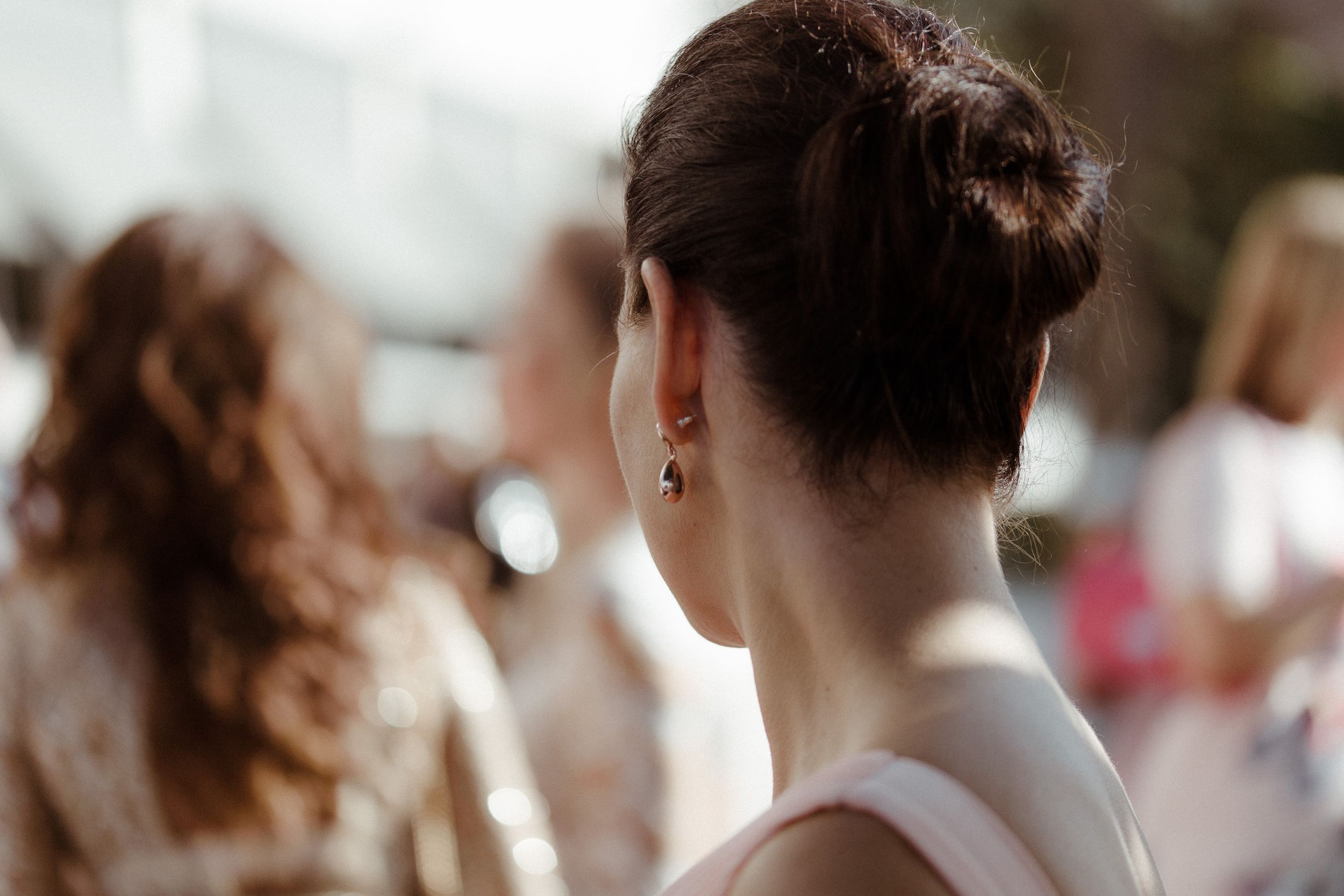 A blurry crowd of people with bokeh effect against bright background in soft focus.