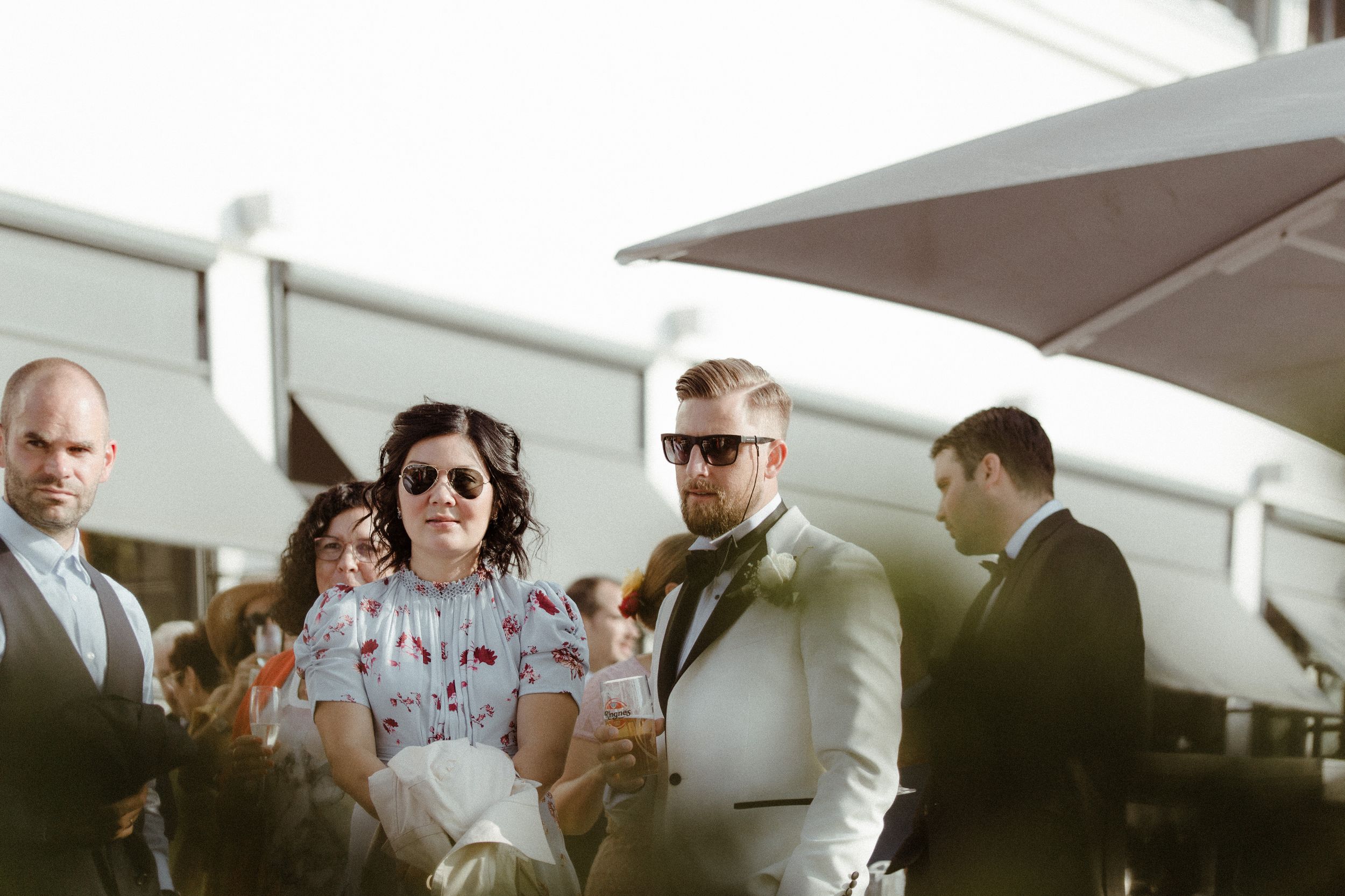 Guests celebrating and socializing at an elegant outdoor event venue with white decor.