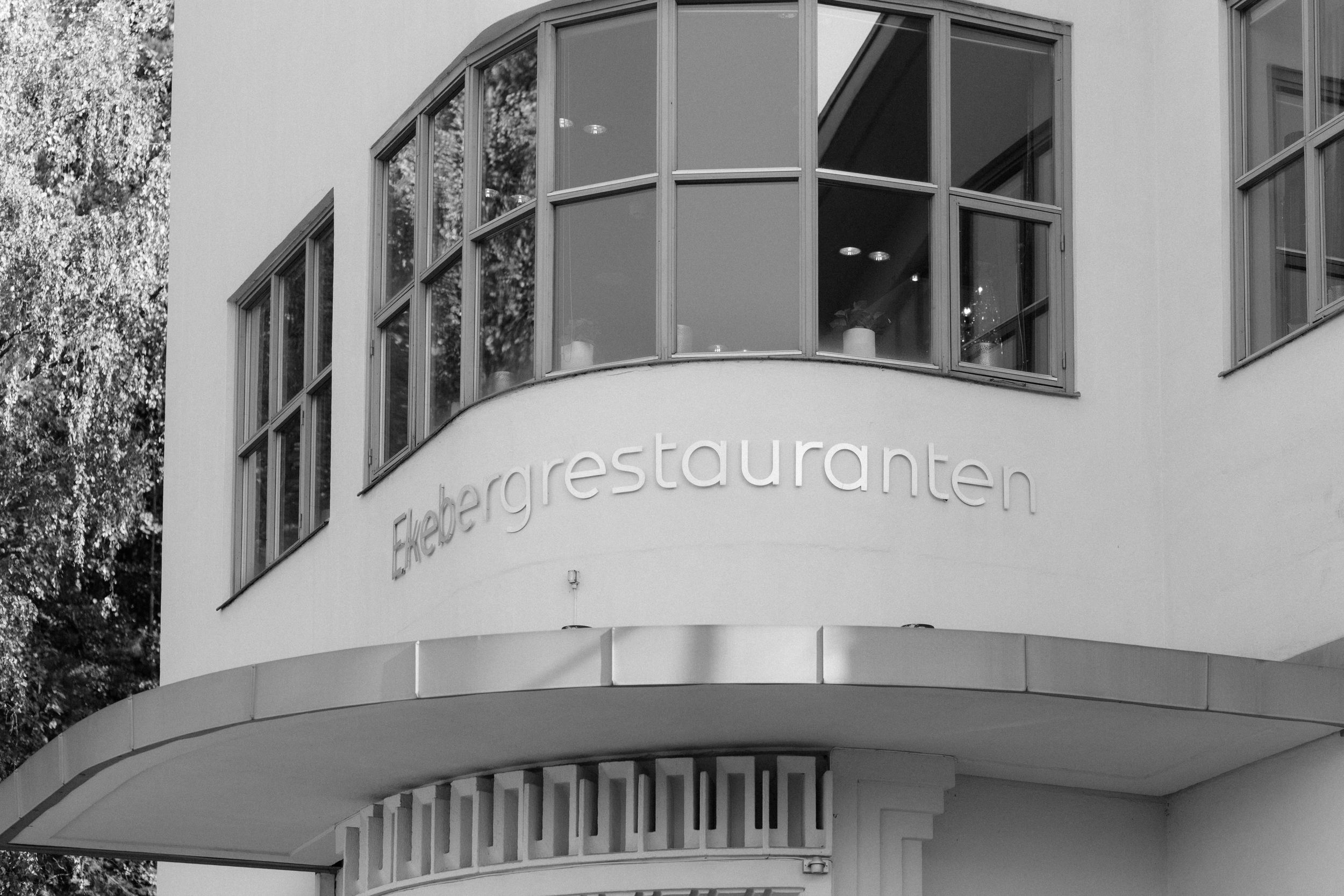Exterior view of modern design apartments with curved facade and windows, featuring restaurant and commercial spaces.